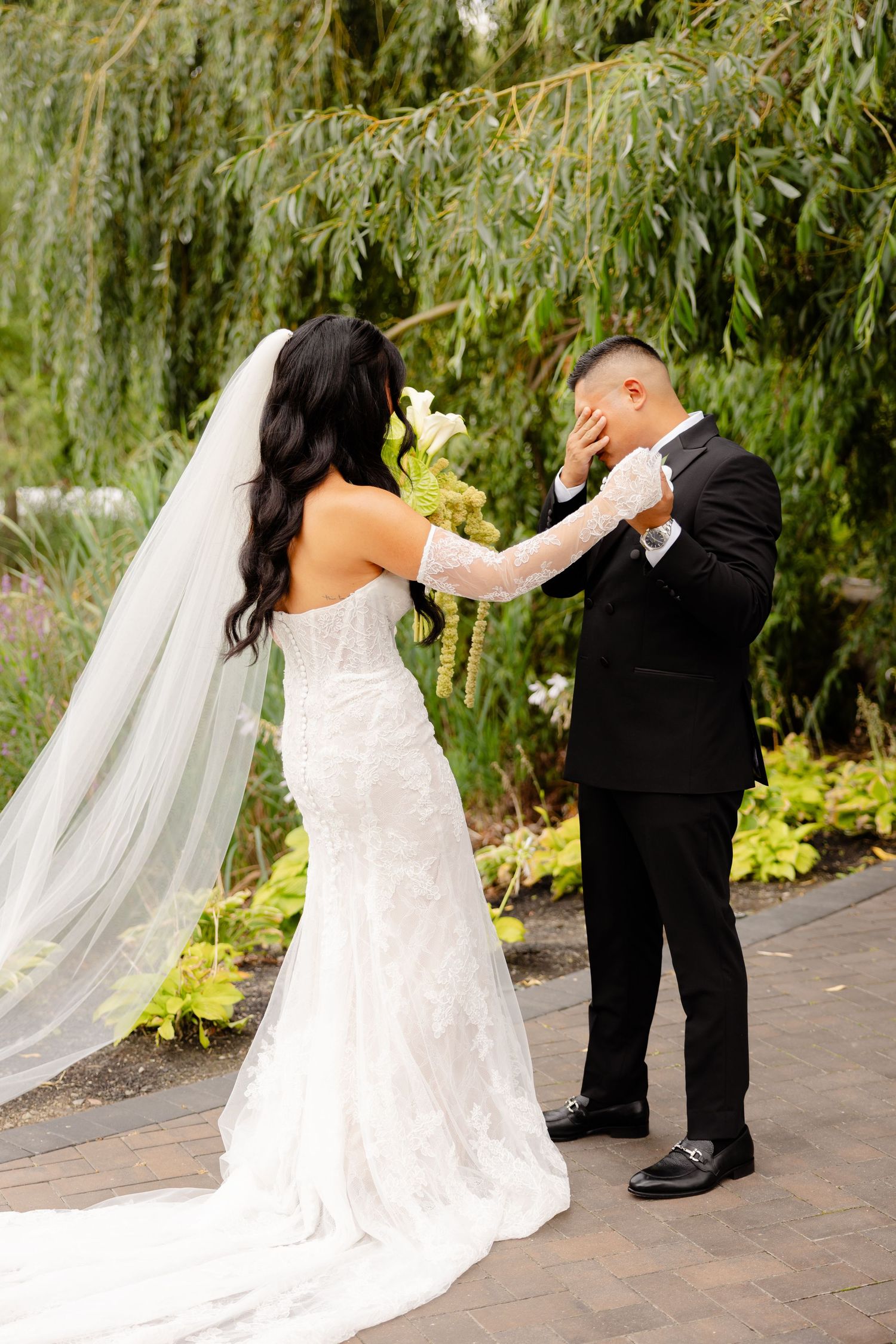 Elegant bride and groom sharing a romantic moment under a willow tree during their wedding ceremony.