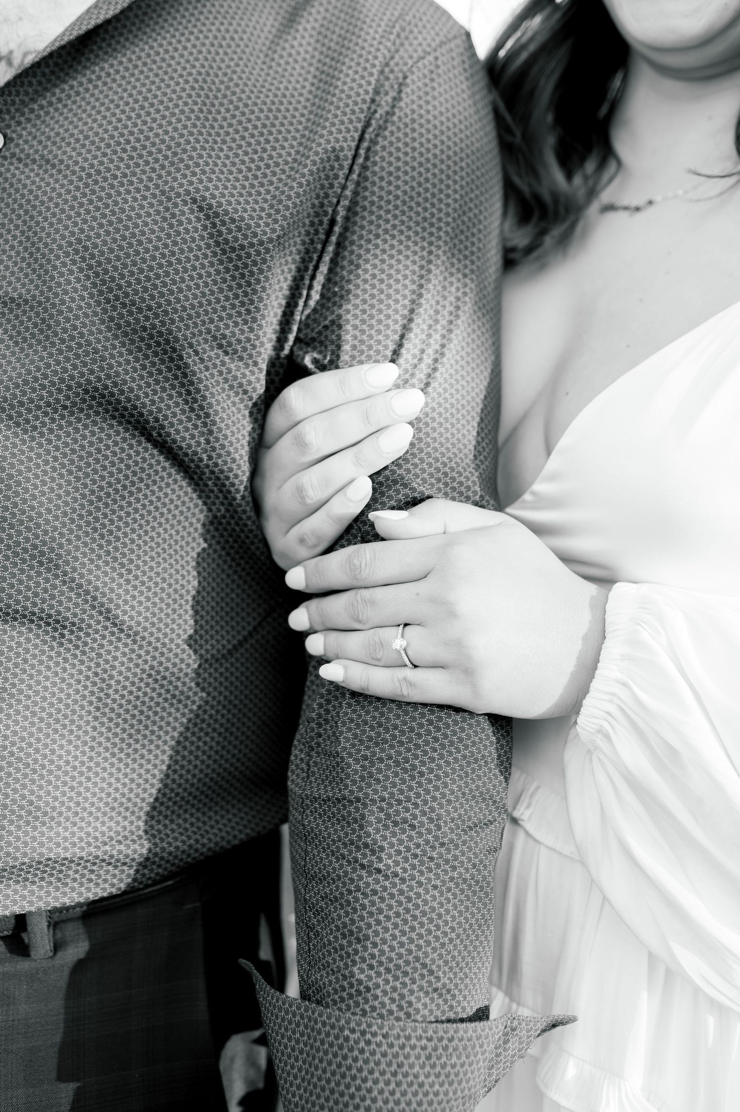 Close-up black and white photo showing hands holding onto dress shirt sleeve.