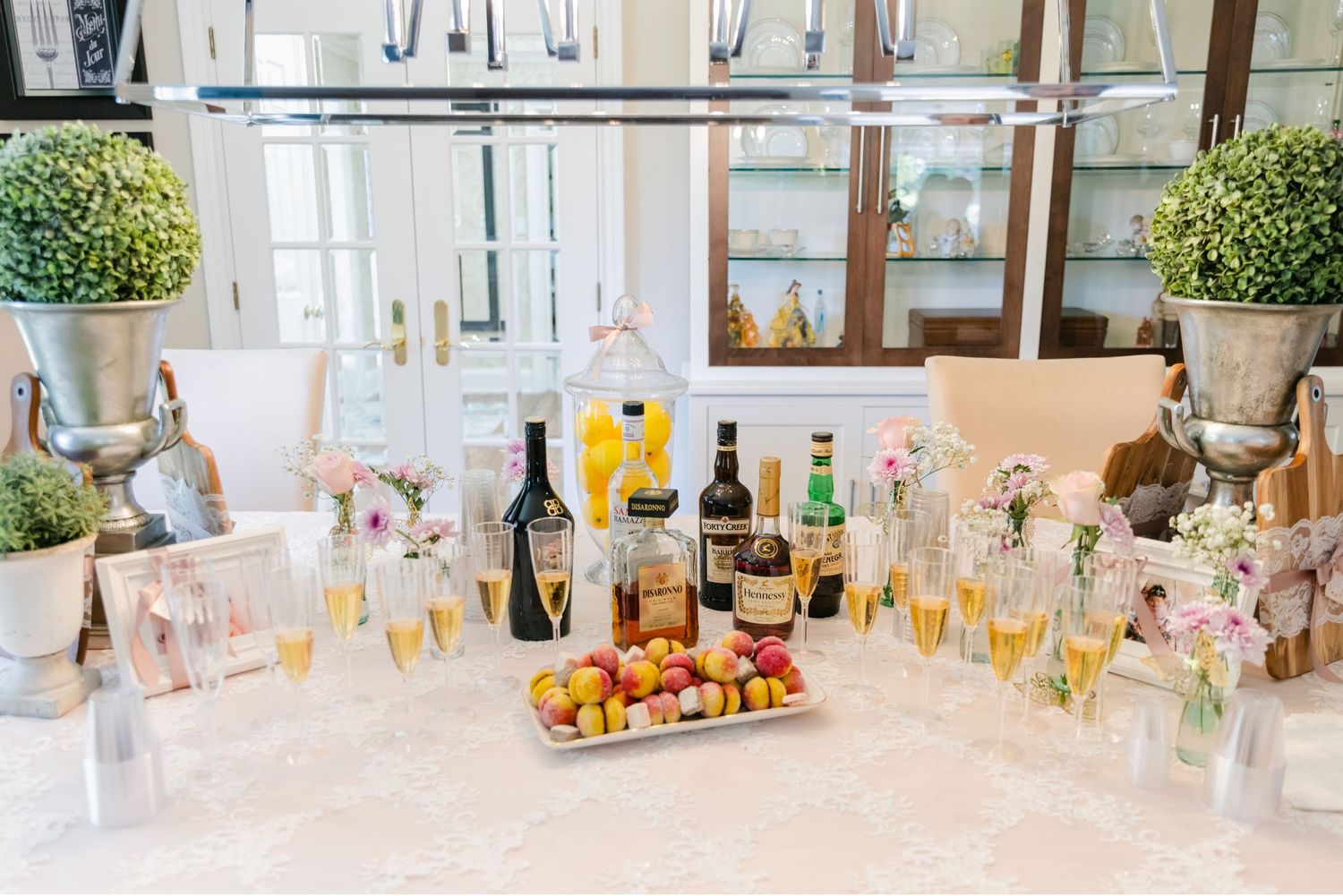 Elegant drink station with champagne, wine bottles, and fresh fruits displayed on a marble counter.