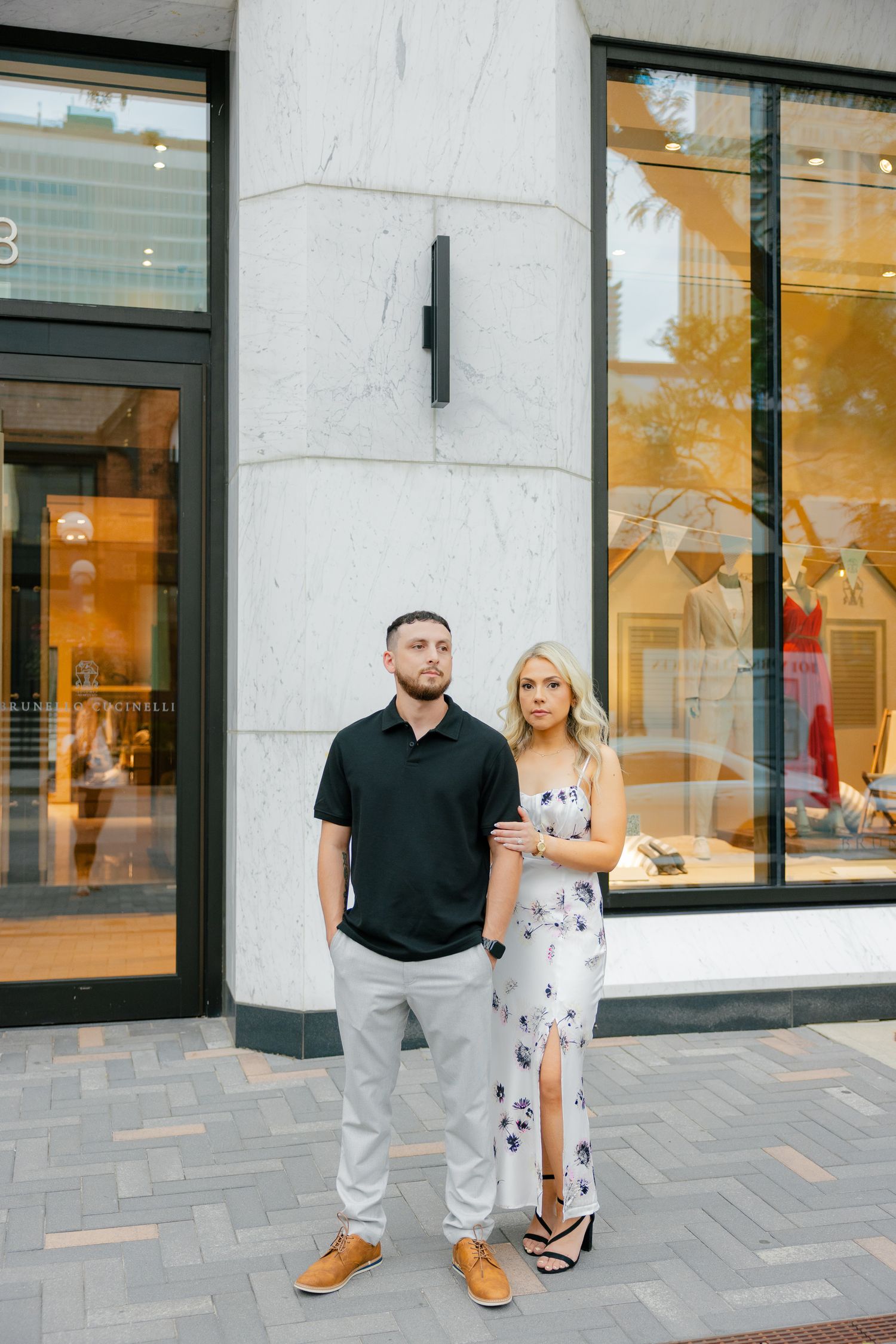 Couple stands in front of a boutique storefront wearing coordinating black and white outfits.