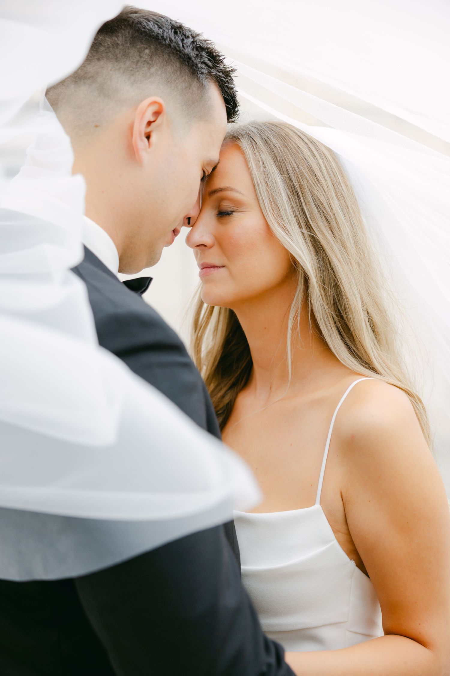 Tender close-up moment between newlyweds with soft natural lighting and romantic composition.