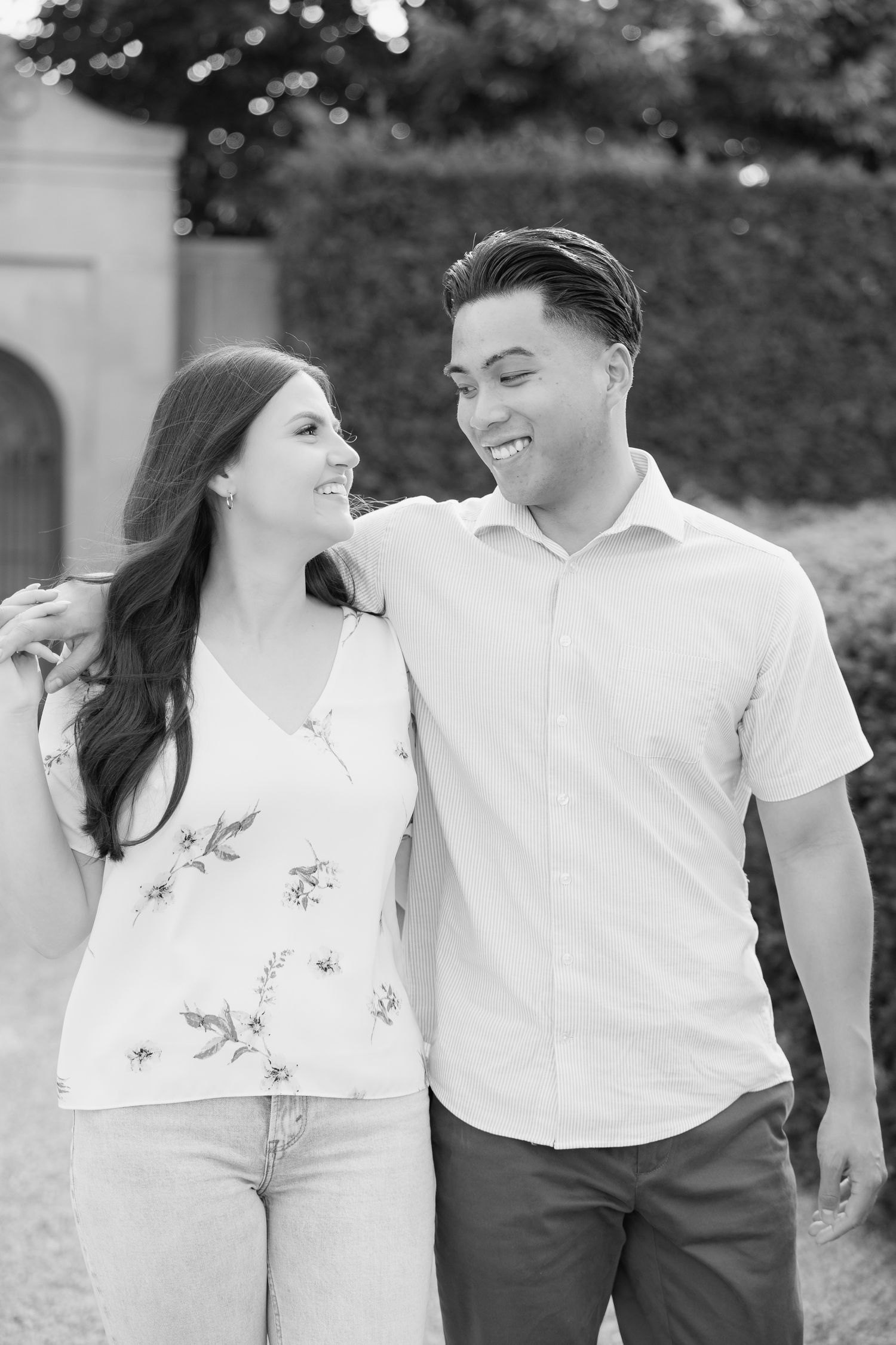 A black and white portrait of a couple sharing a tender moment in a garden setting.