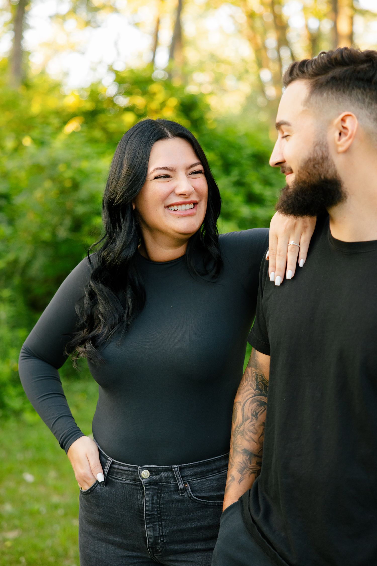 Couple sharing a candid laughing moment while posing outdoors in black attire.