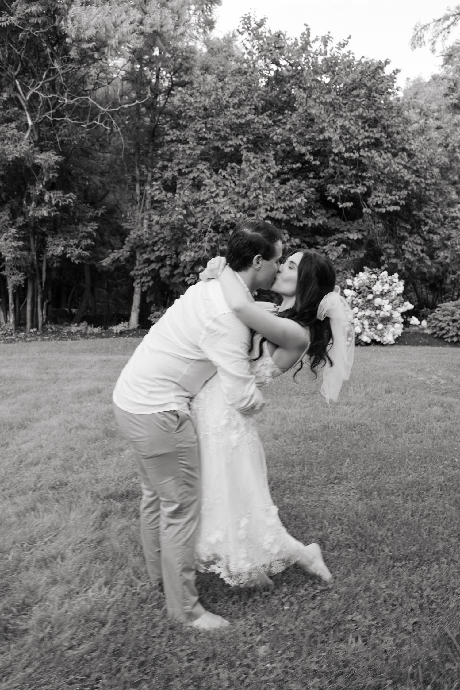 A romantic dip pose captured in black and white during an outdoor wedding photoshoot.