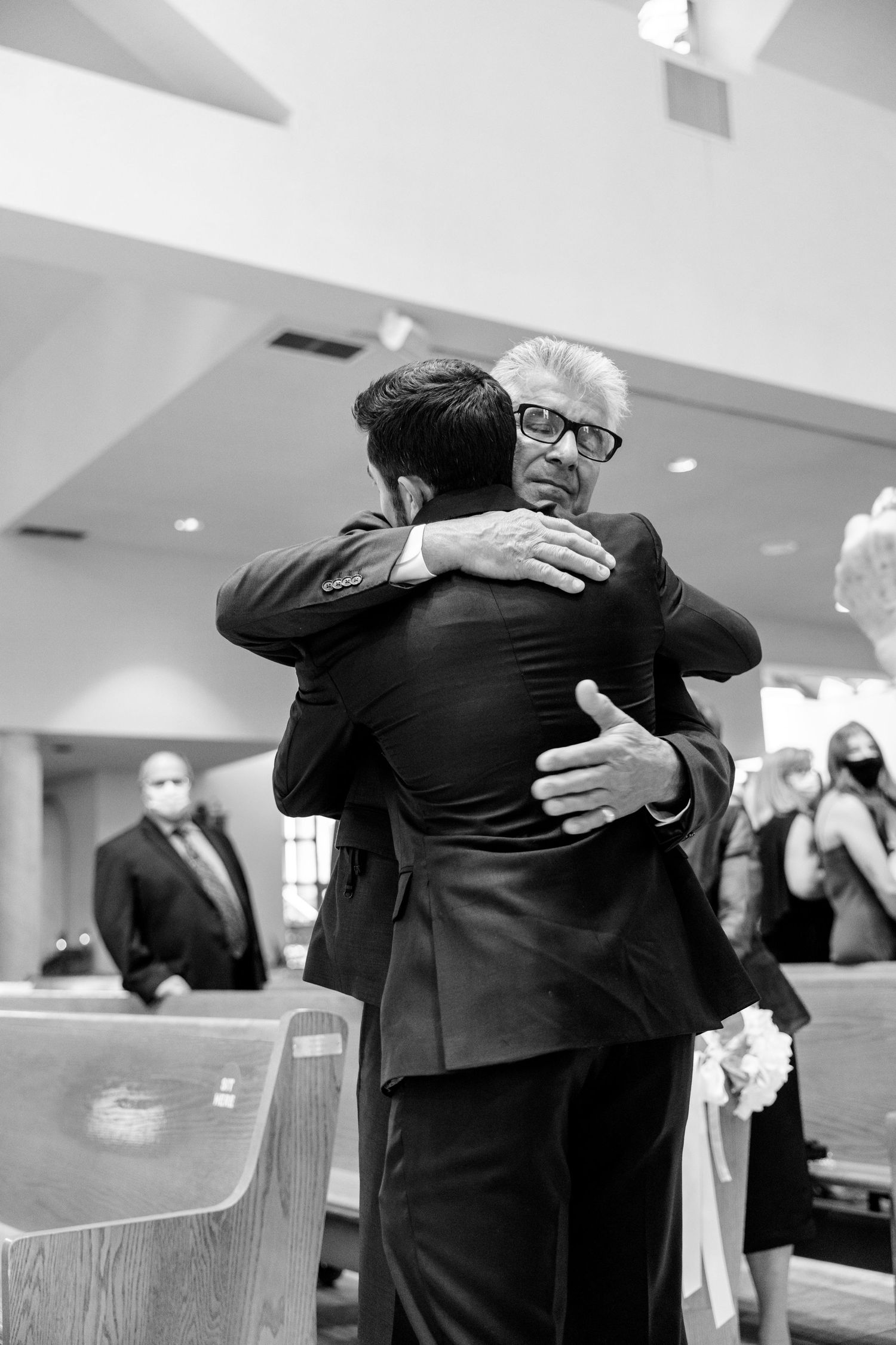 Black and white photo of an emotional embrace during a wedding ceremony.