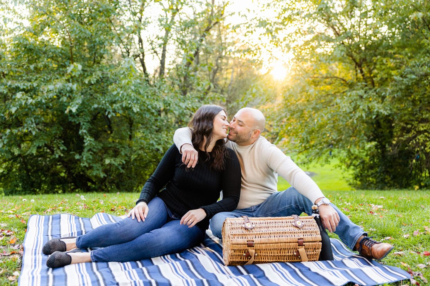 Couple sharing romantic moment on picnic blanket during golden hour in park.