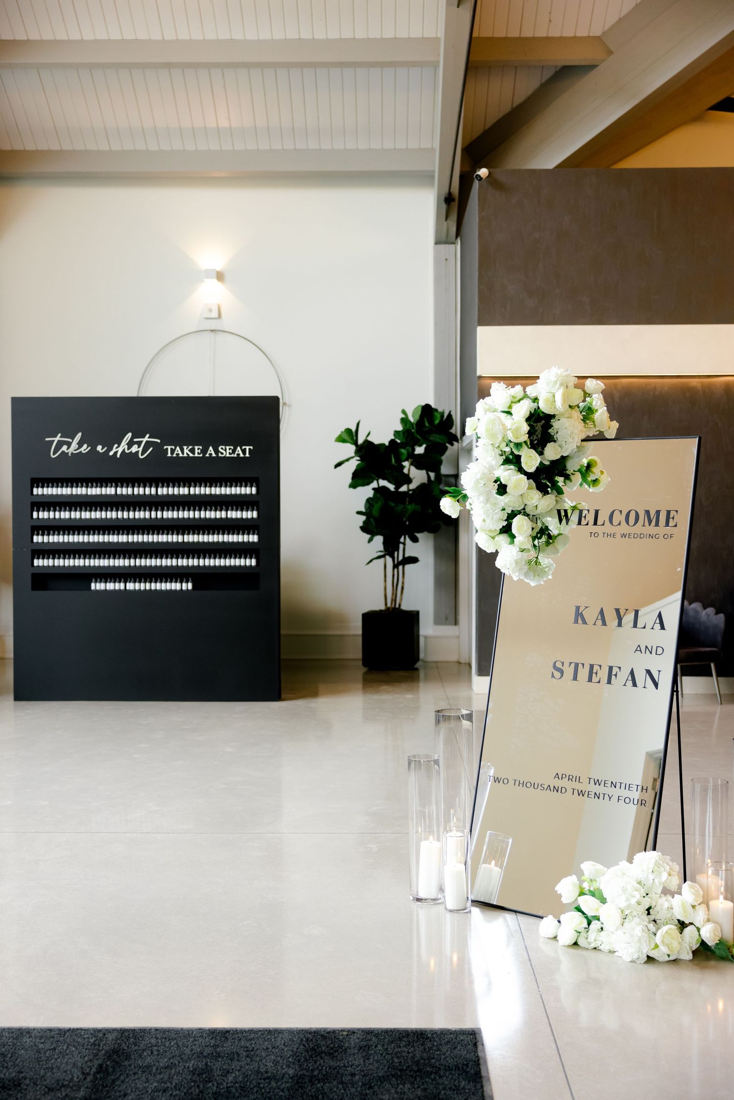 Wedding venue setup with seating chart and welcome sign decorated with white florals.