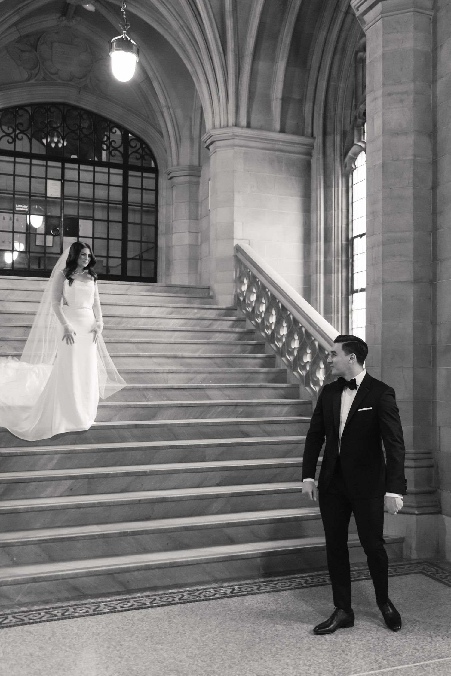 Black and white wedding portrait showcasing couple on elegant stone staircase.