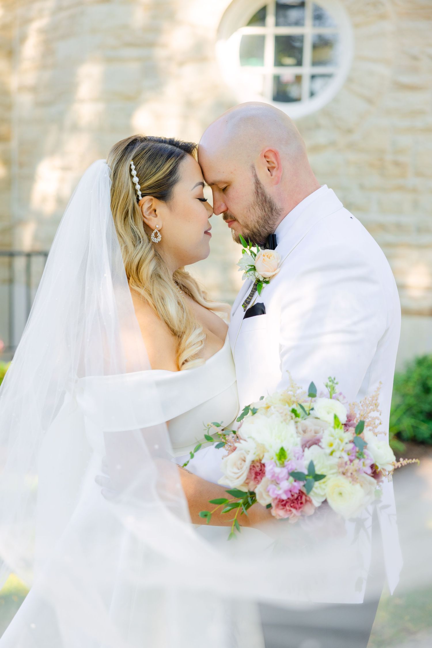 A tender moment between newlyweds with soft lighting and flowing white veil.