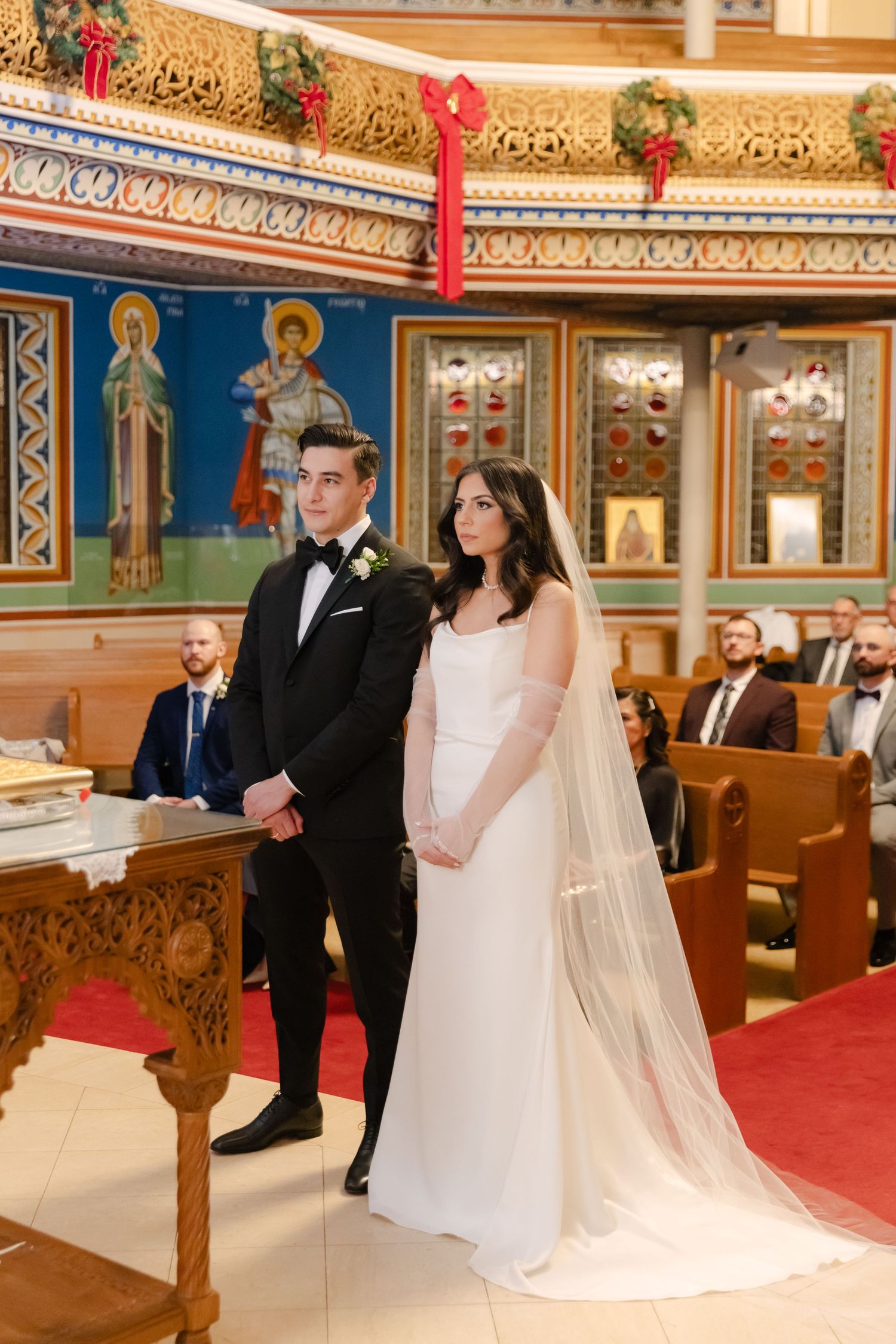 Elegant church wedding with couple standing before decorated altar and wooden pews.