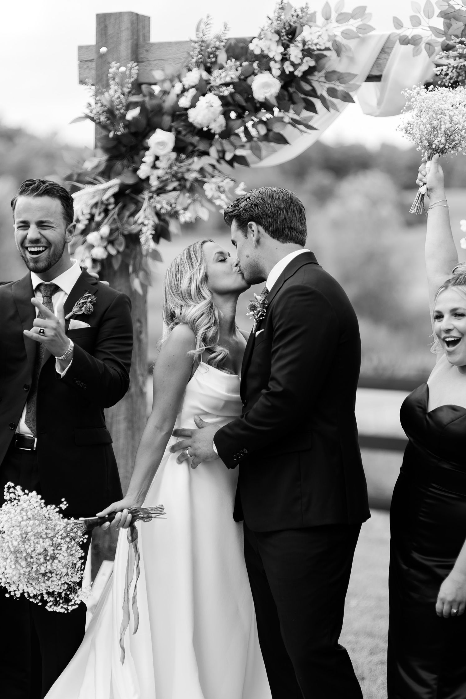 Black and white wedding moment captured under floral arch with baby's breath bouquets.
