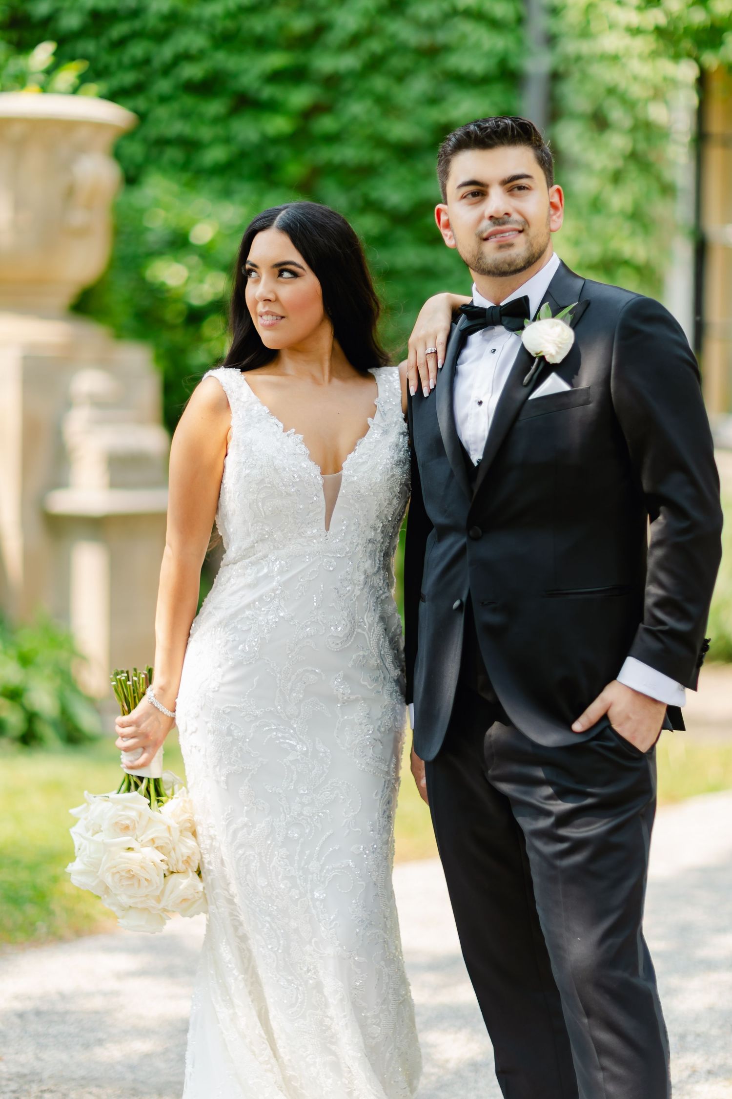 Elegant wedding portrait of a couple in formal attire standing together in a garden setting.
