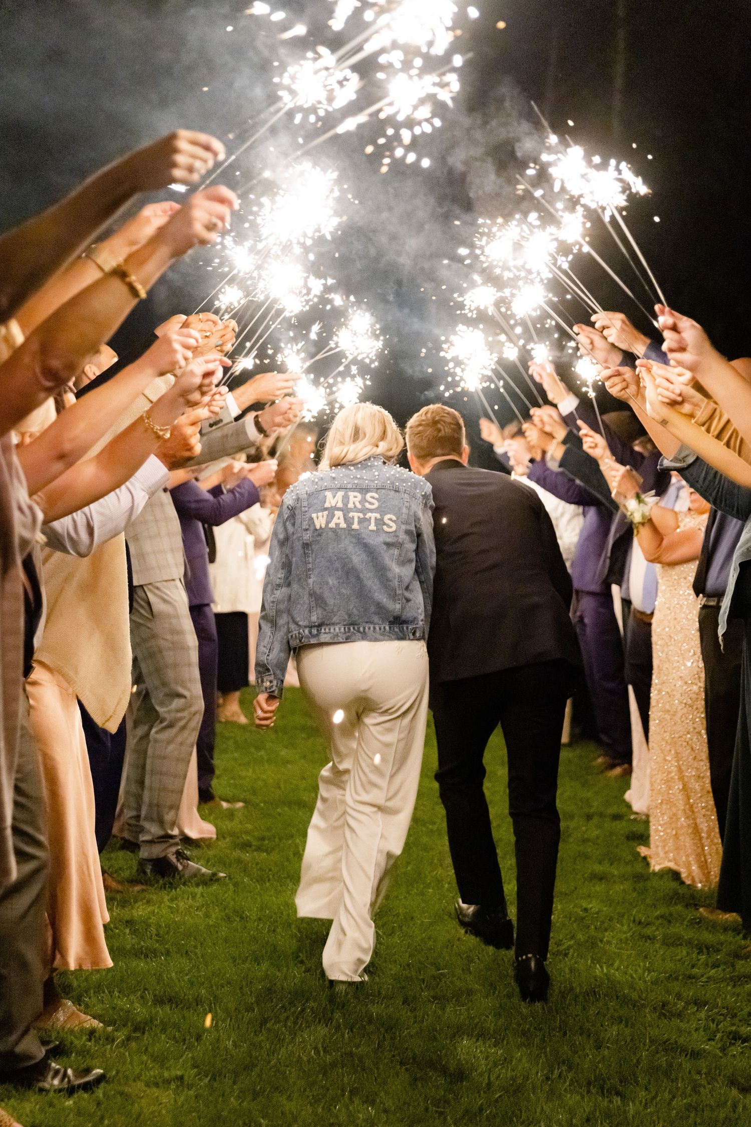 Wedding guests hold sparklers creating a magical tunnel exit for the departing couple.