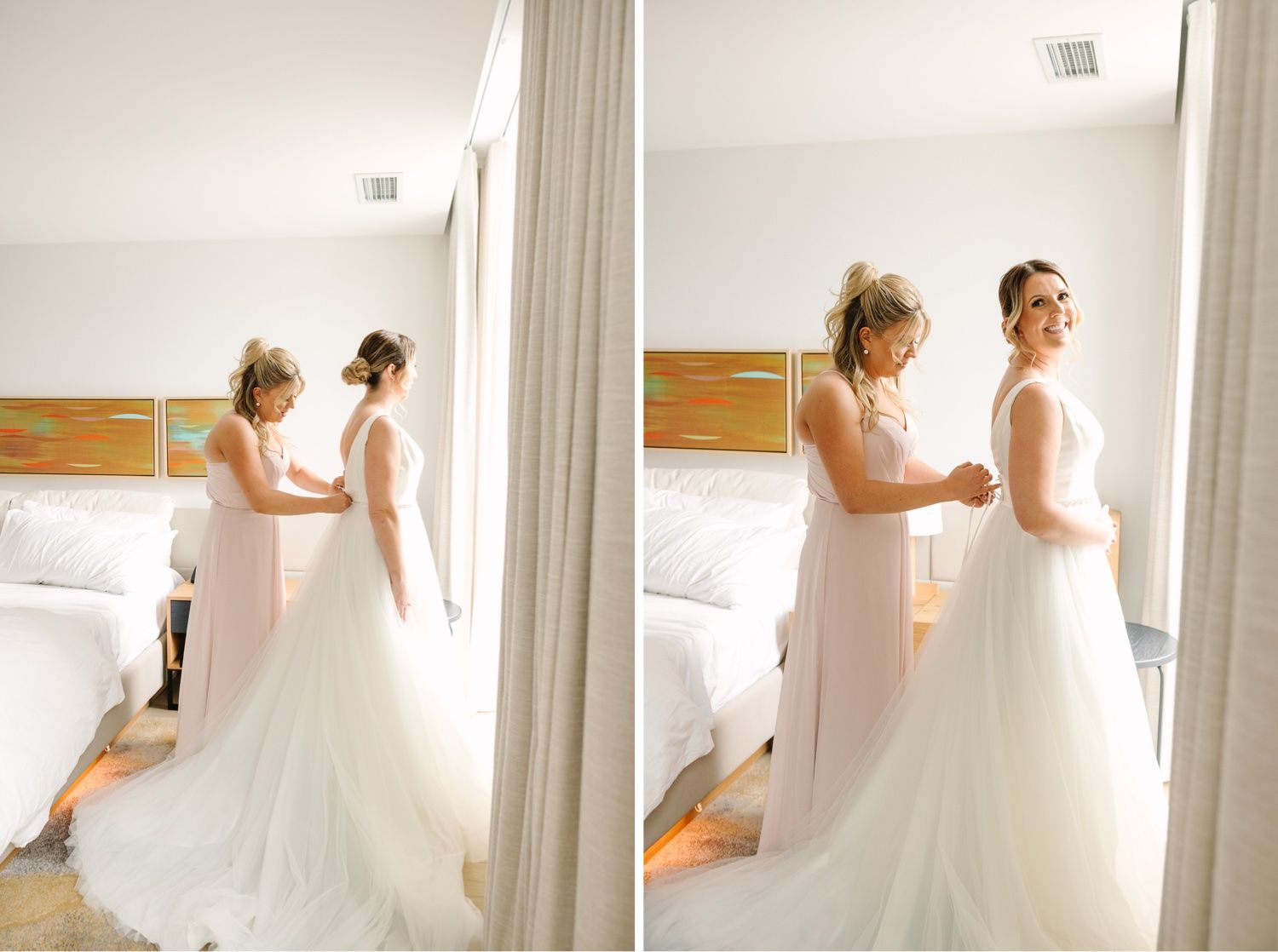 Two women helping with wedding dress preparation in bright white room.