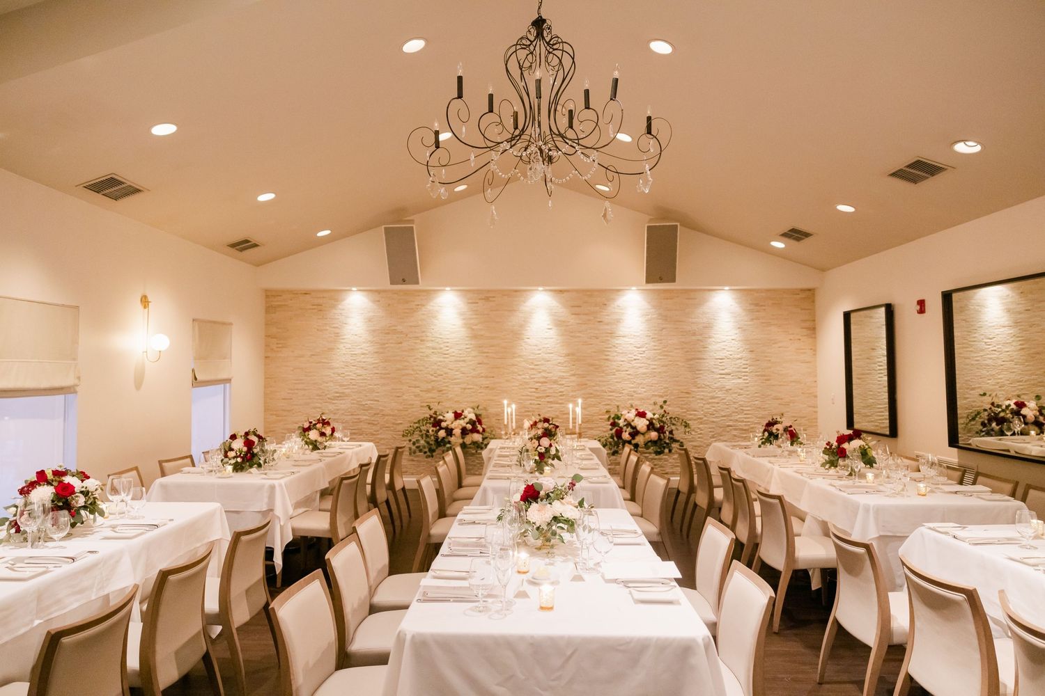 Elegant wedding reception room with crystal chandelier and multiple round tables set with white linens.