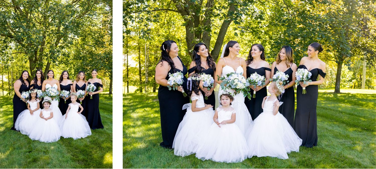 Wedding party in black dresses and white gowns pose together in garden setting.