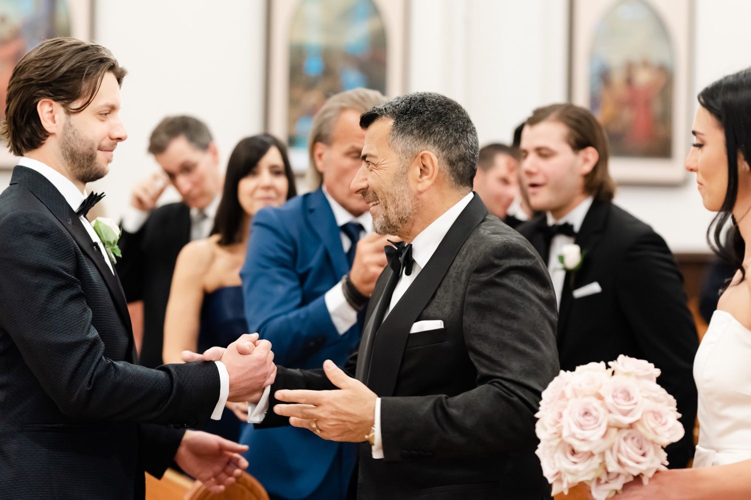 Wedding guests and participants exchanging greetings during a ceremony in an ornate church setting.