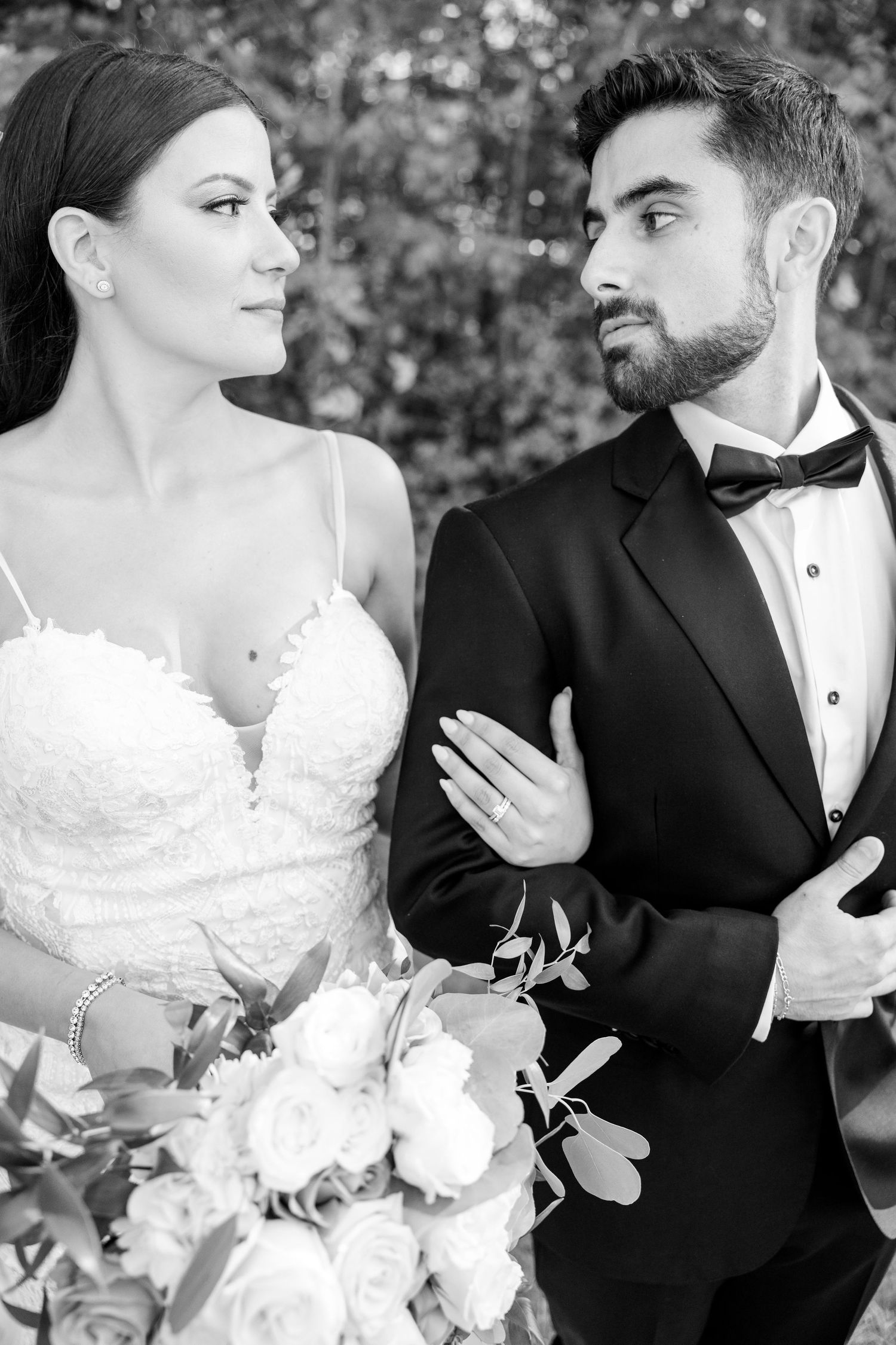 Classic black and white portrait of newlyweds with elegant bouquet and formal attire.