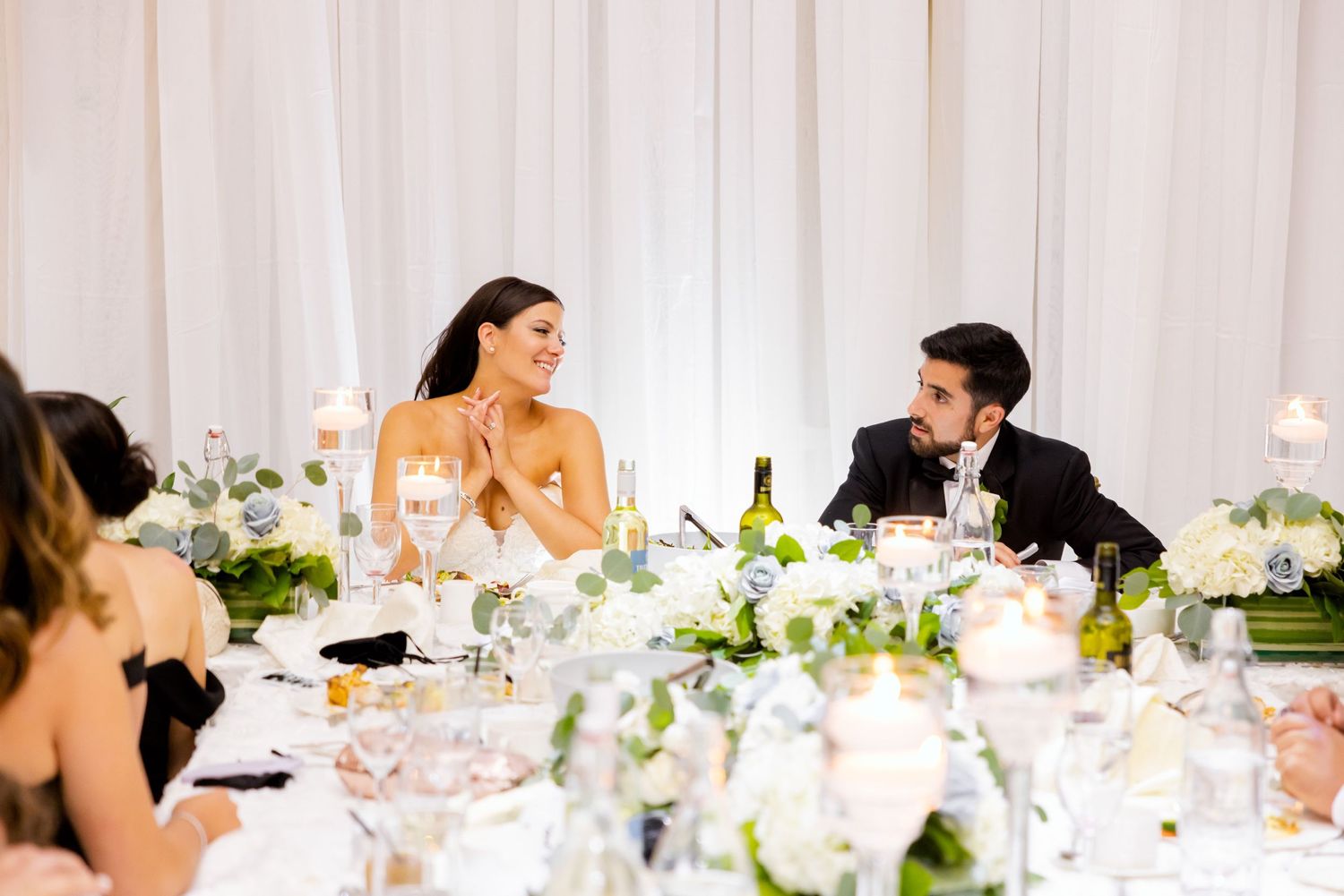Candid moment captured during wedding reception dinner with elegant table settings.