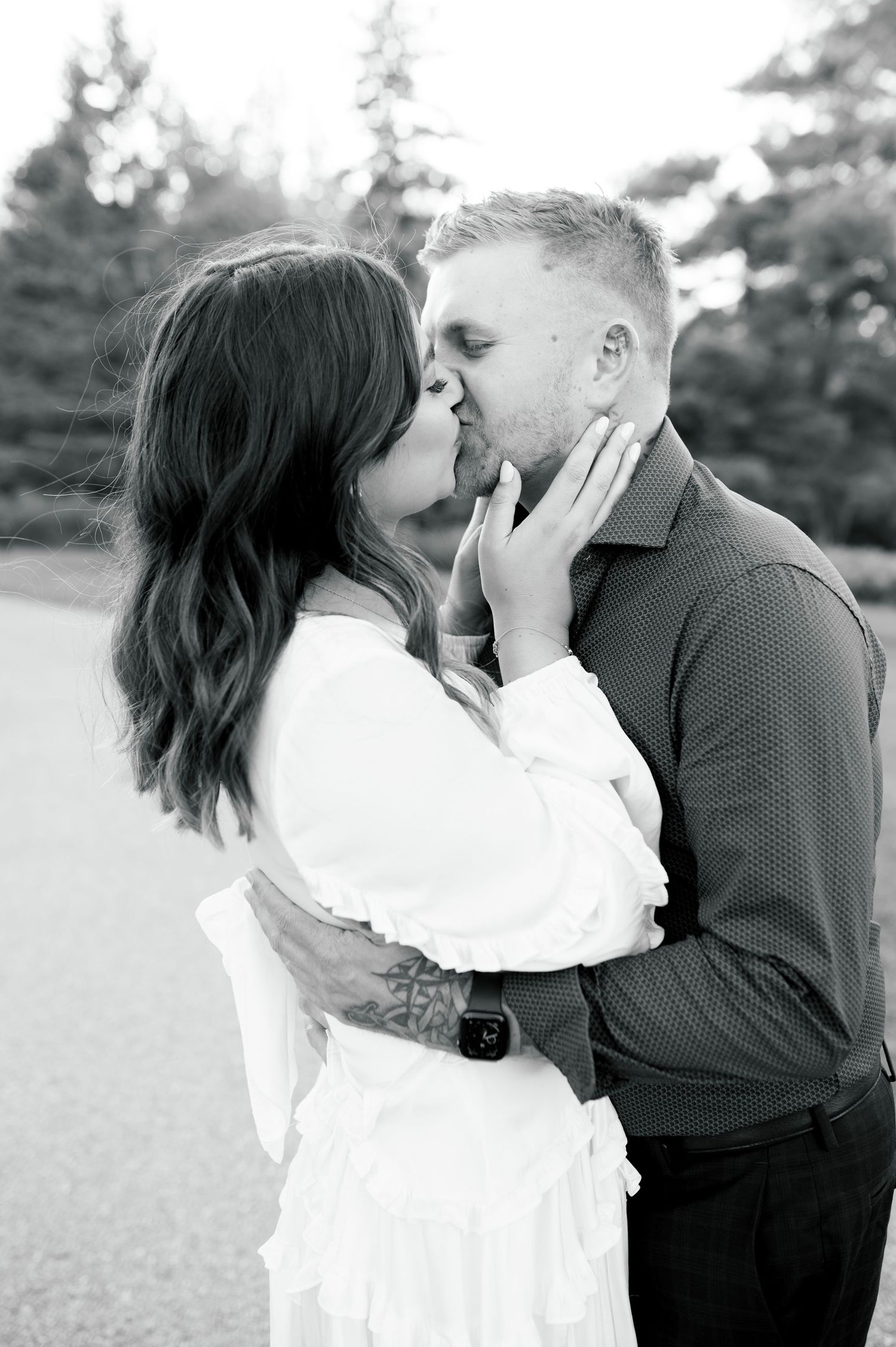 Black and white portrait of couple sharing intimate moment outdoors.