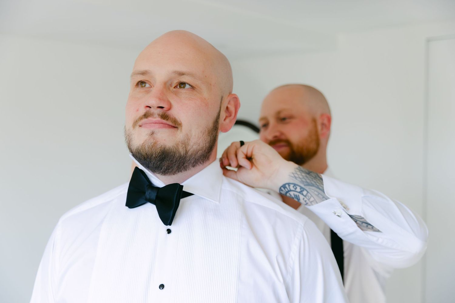 A person adjusting bow tie in formal white shirt during preparation.
