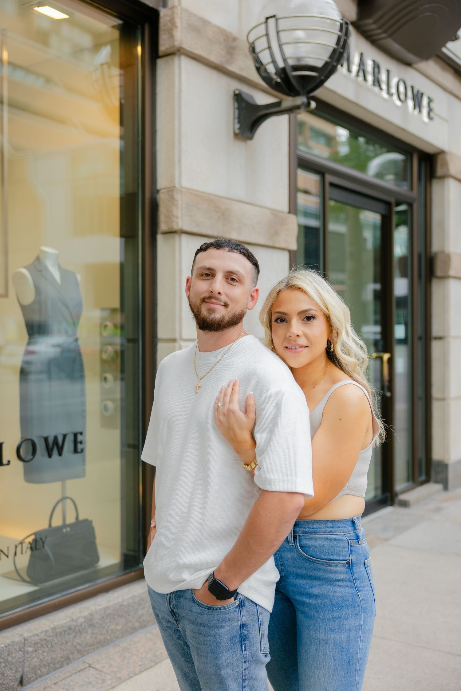 Couple standing outside Marlowe store wearing matching white tops and denim.