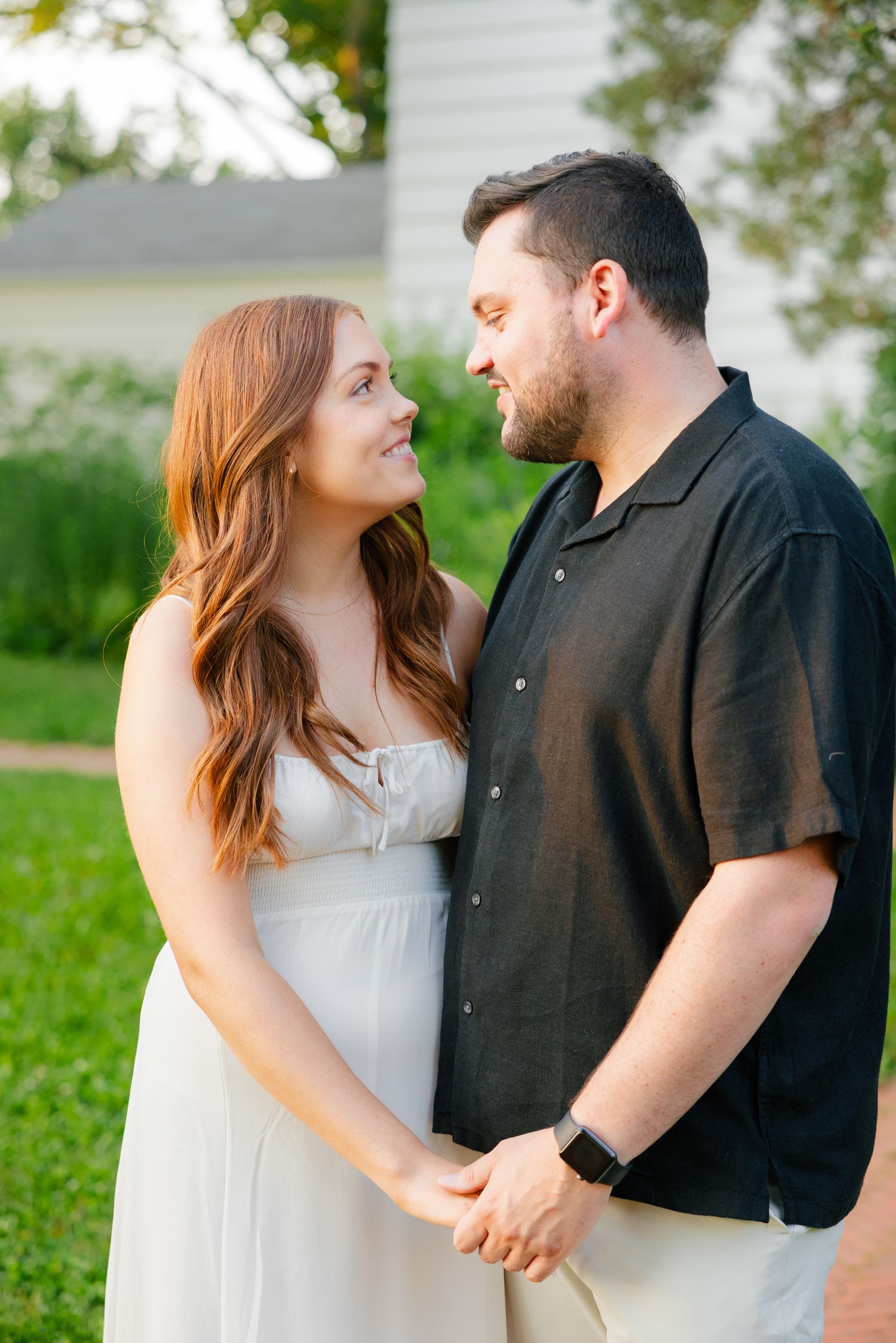 A couple shares an affectionate moment while holding hands on a brick pathway.
