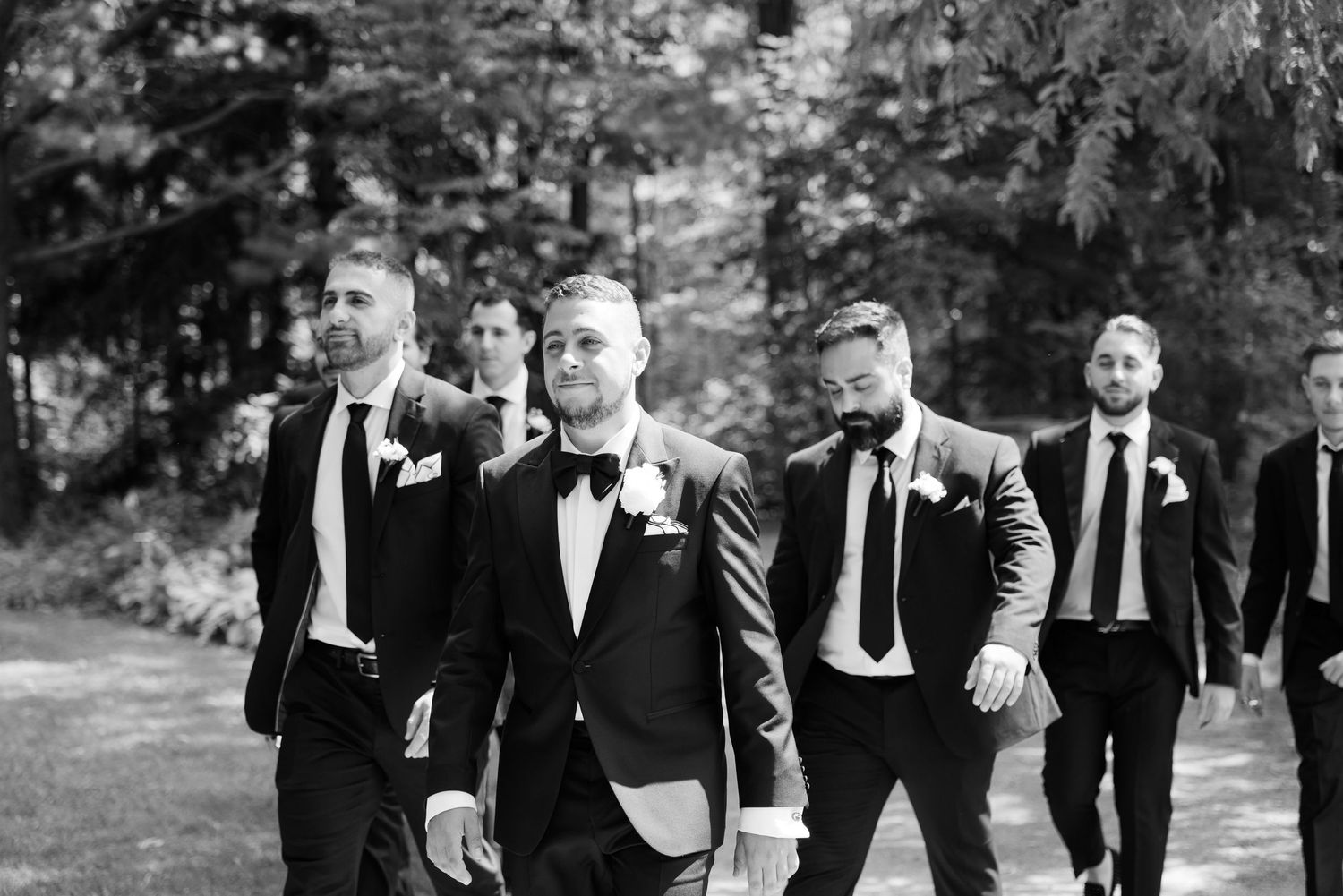 A candid black and white photo of groomsmen walking together outdoors.