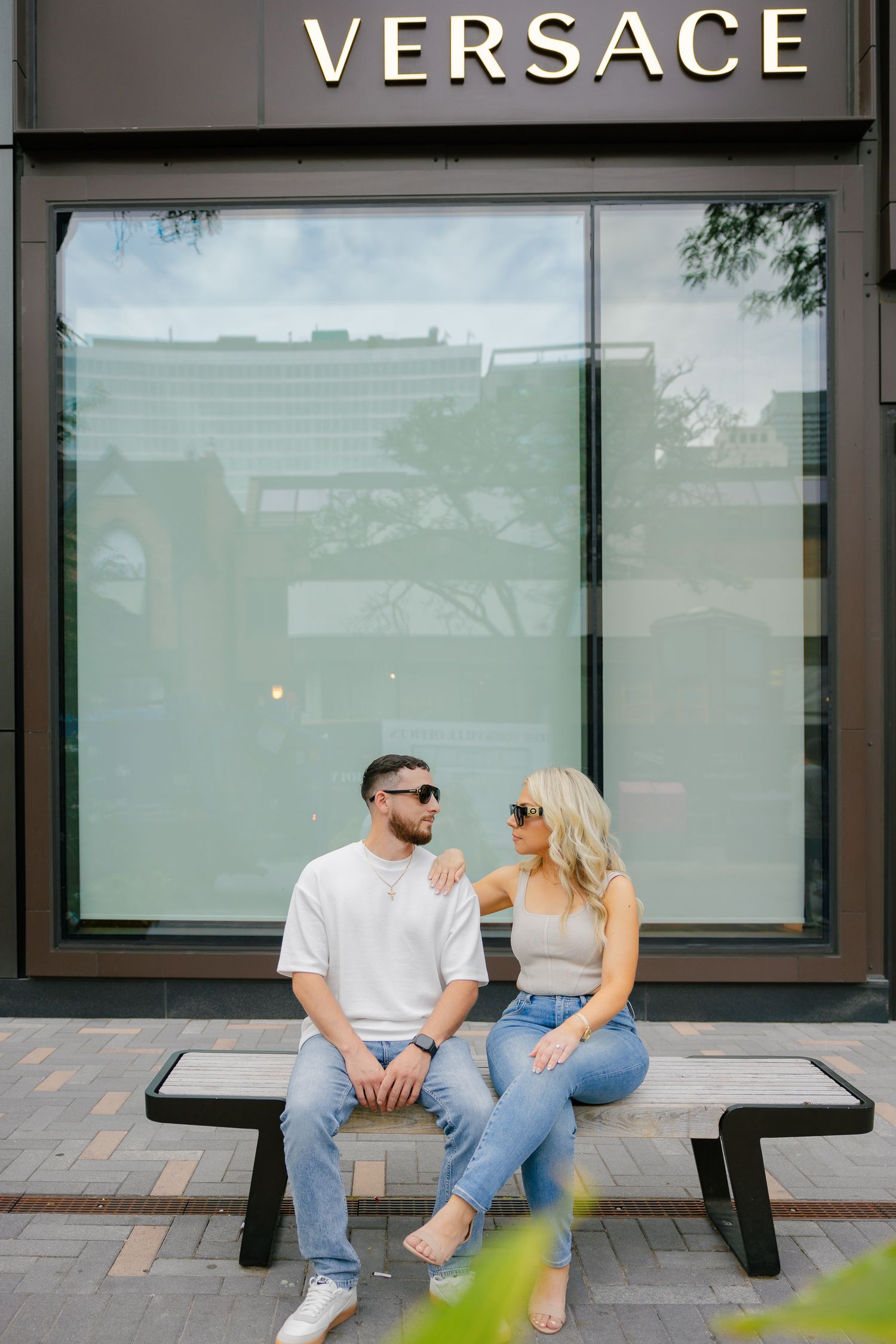 Couple sharing a moment while sitting outside Versace storefront.