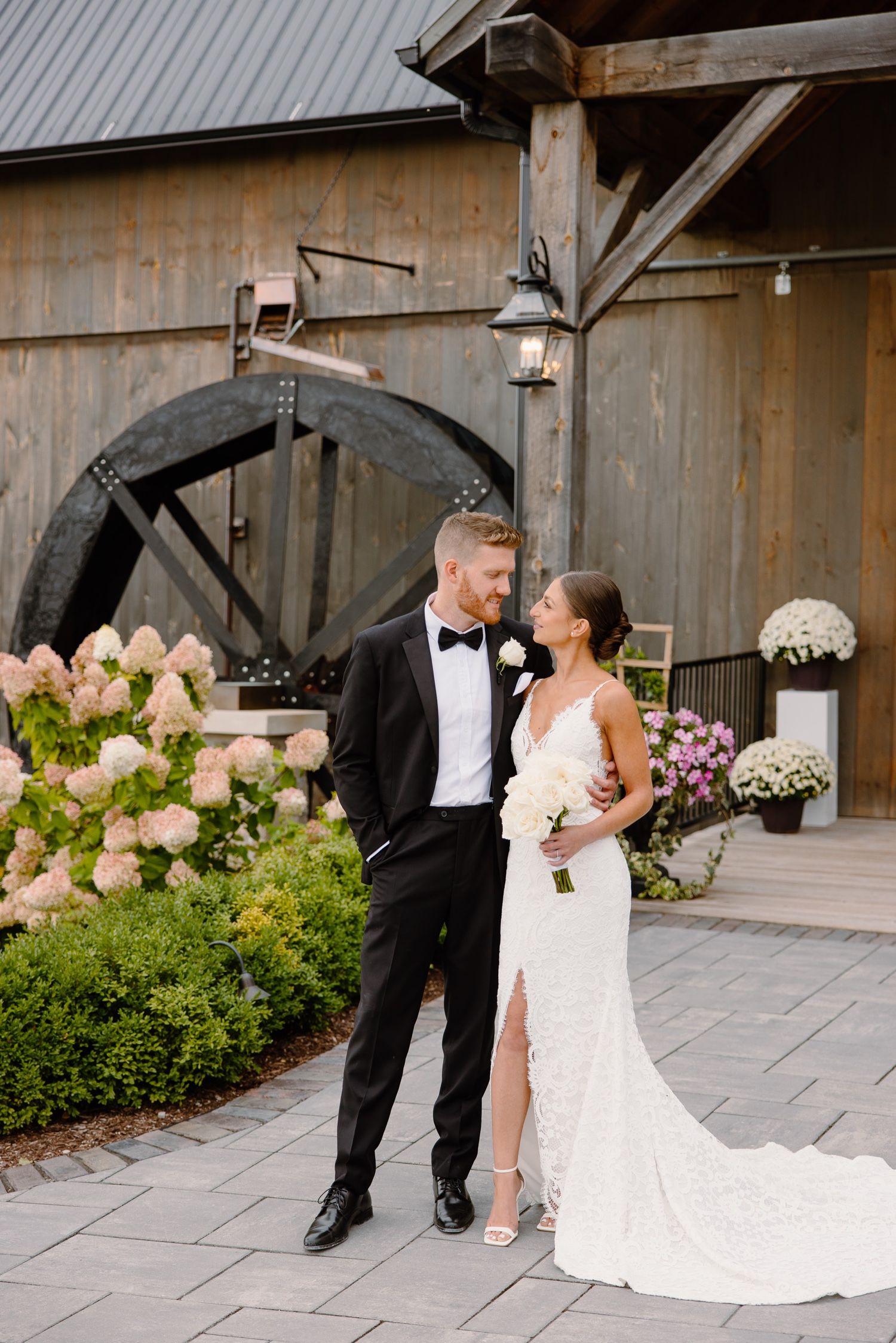 Beautiful garden wedding setting with antique water wheel and lantern lighting creates romantic atmosphere.