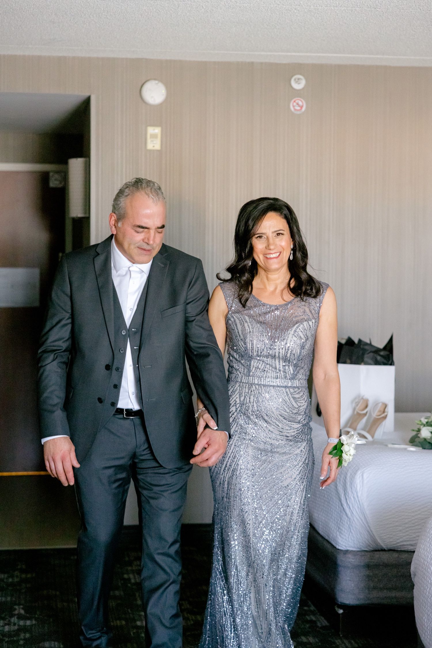 Couple in formal attire walking together in a hotel room.