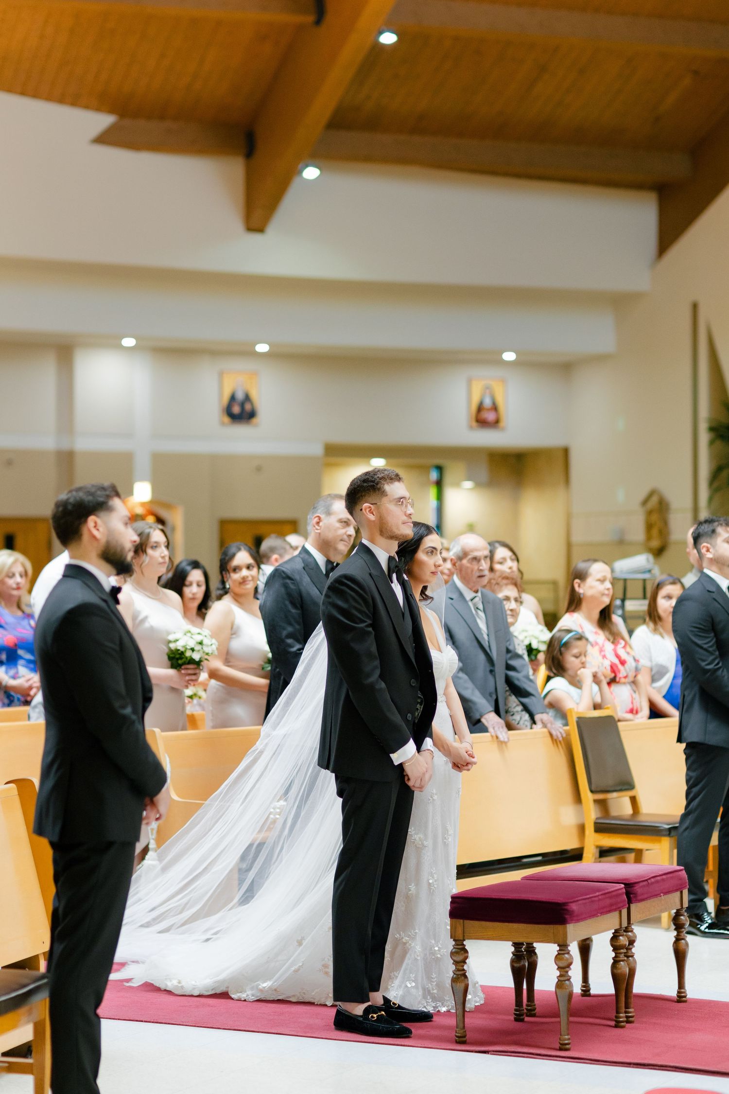Wedding couple stands at the altar during their church ceremony with guests seated behind them.