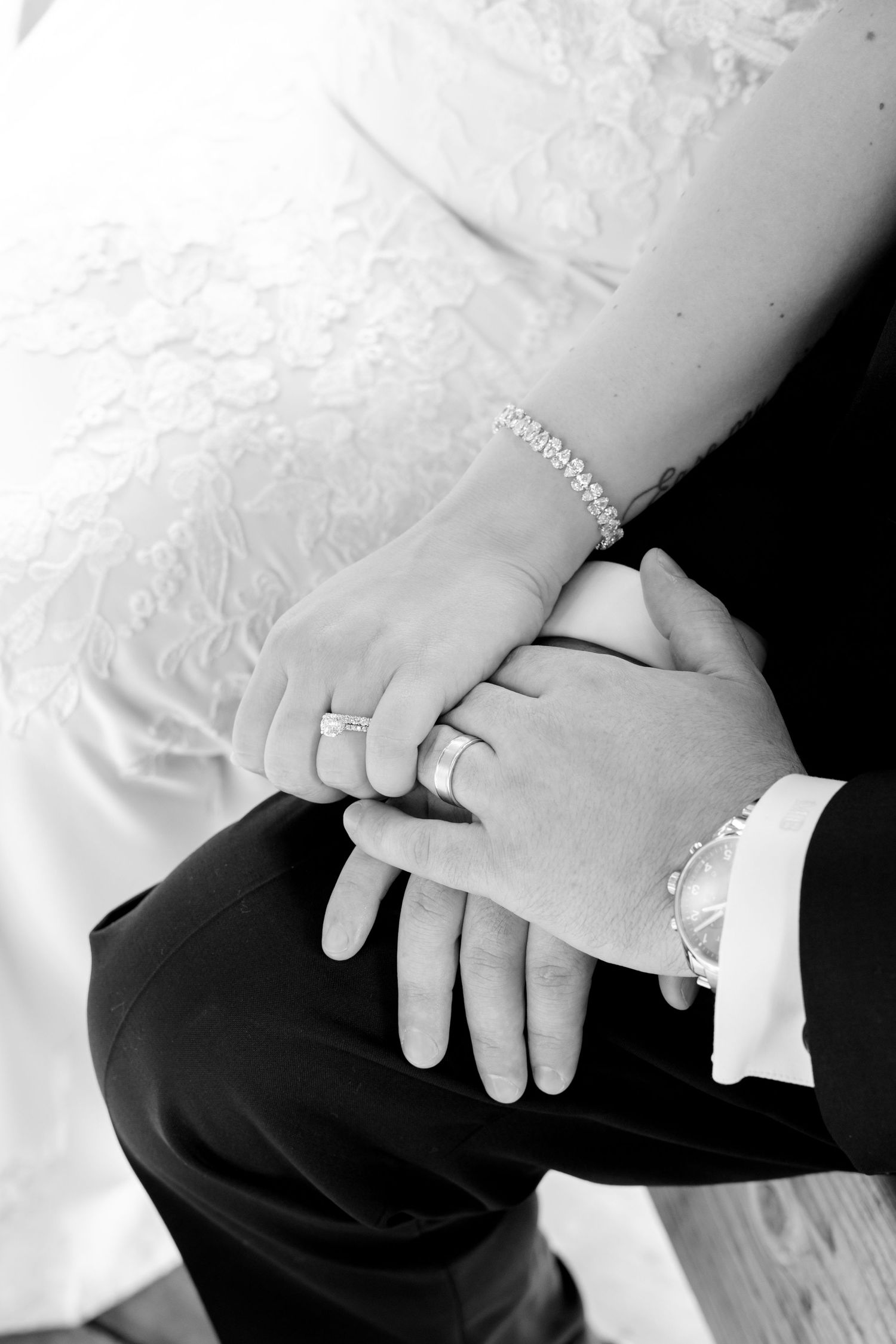 Close-up of wedding rings and clasped hands showing elegant bridal jewelry.
