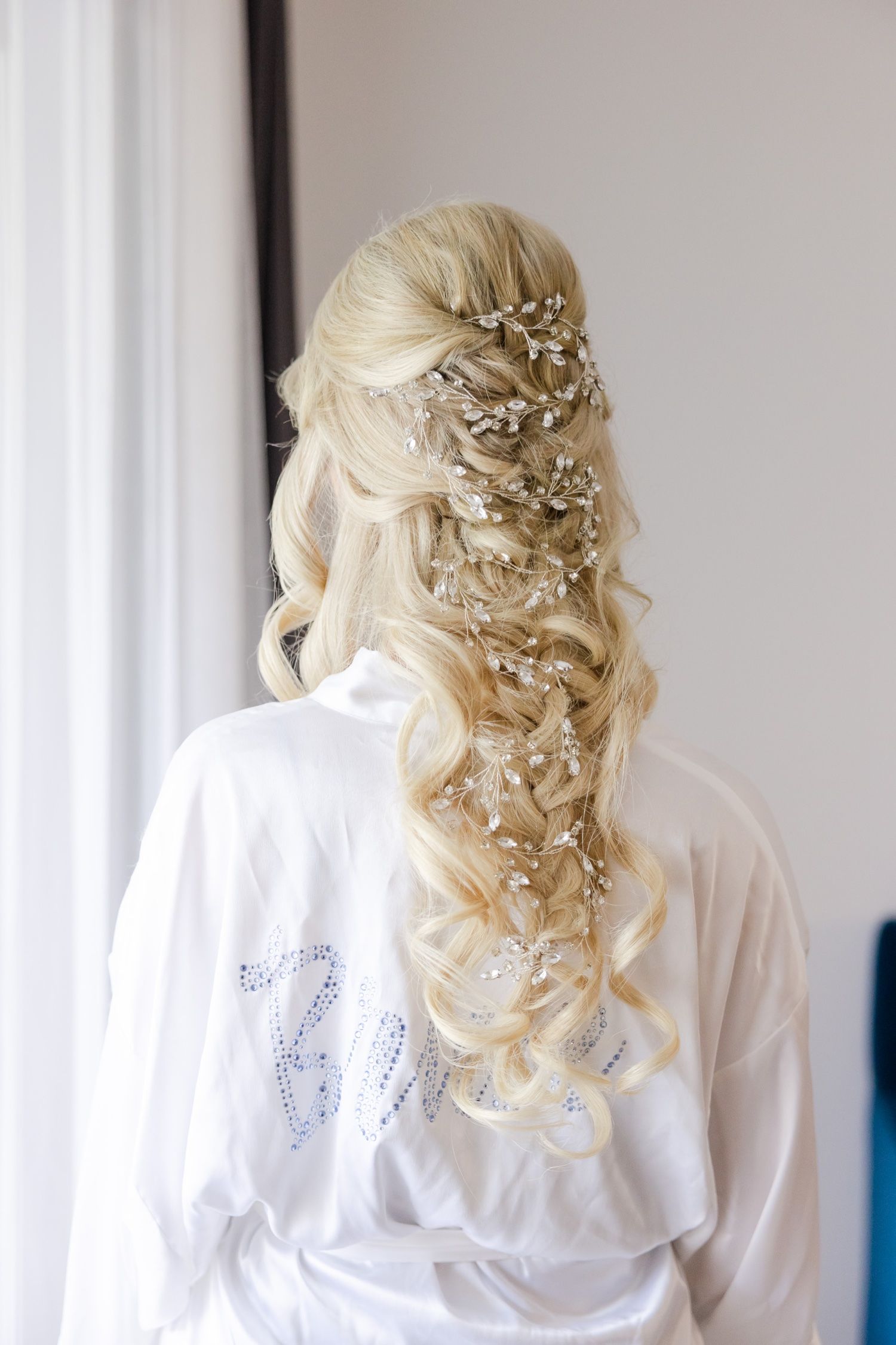 Elegant bridal hairstyle featuring long blonde waves adorned with delicate crystal hair accessories.