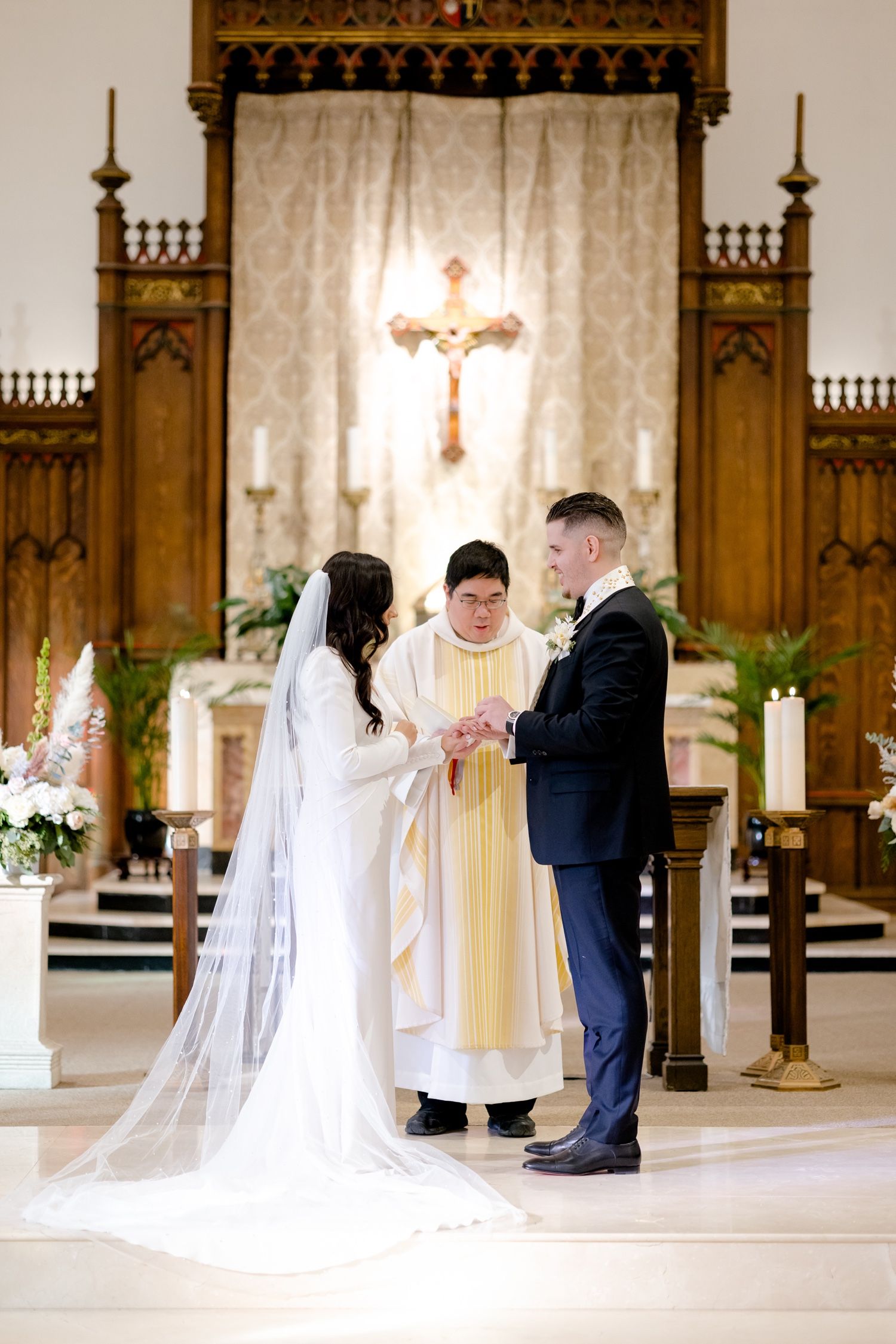 A couple exchanges rings during their wedding ceremony with white floral decorations.