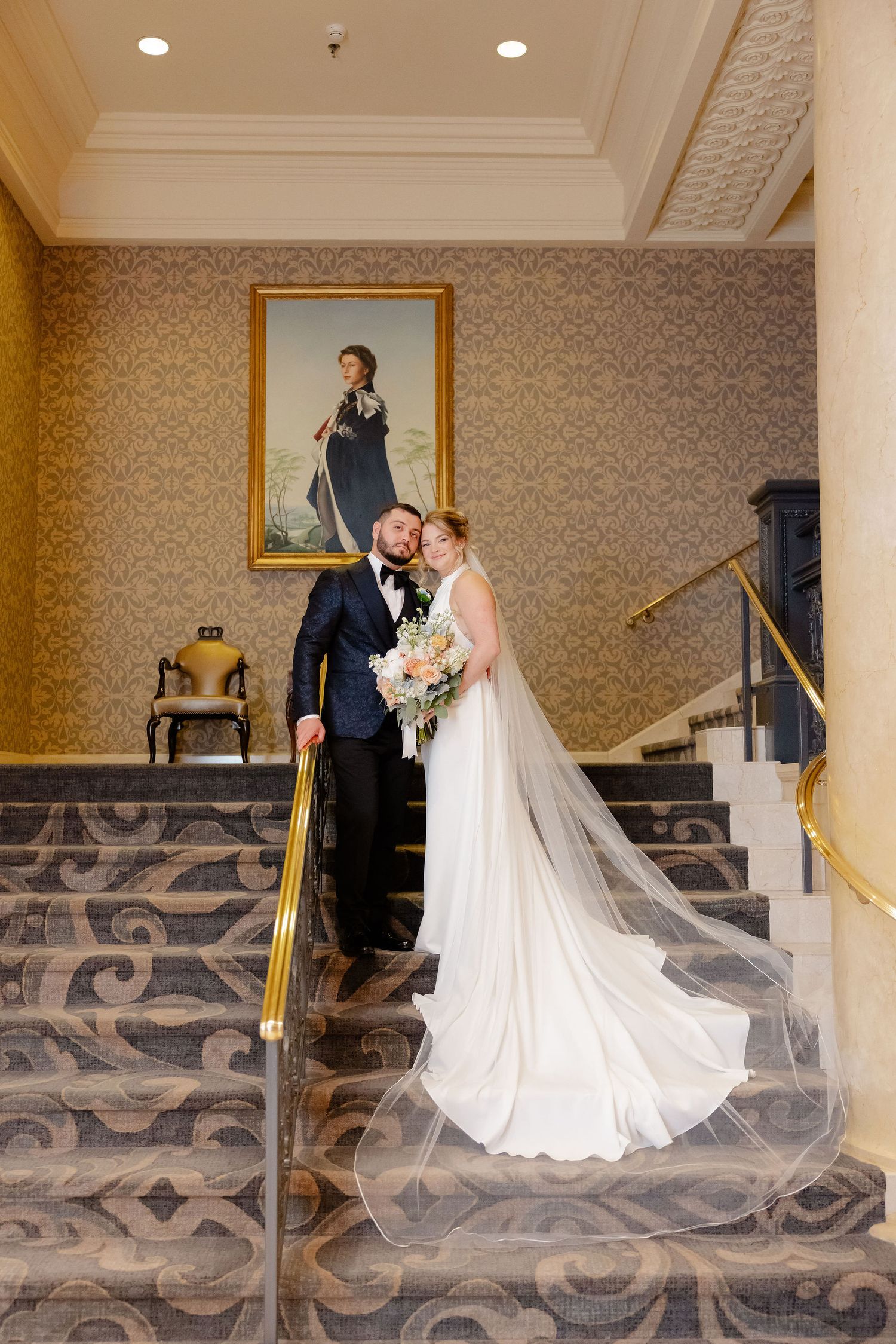 A wedding sequence showing a couple walking down elegant hotel stairs with decorative carpeting.