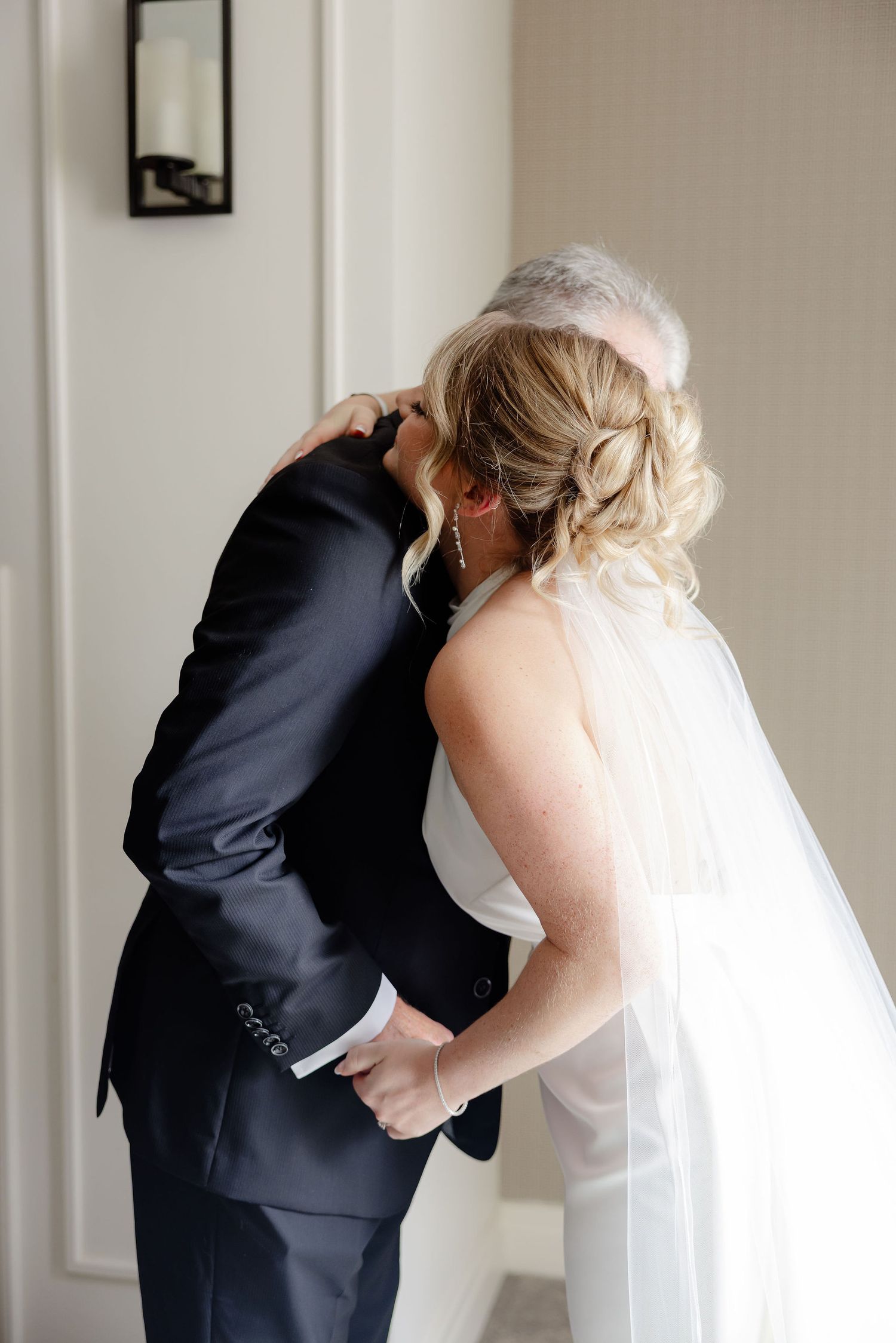 A series of emotional first look moments between a bride in white and someone in a dark suit.