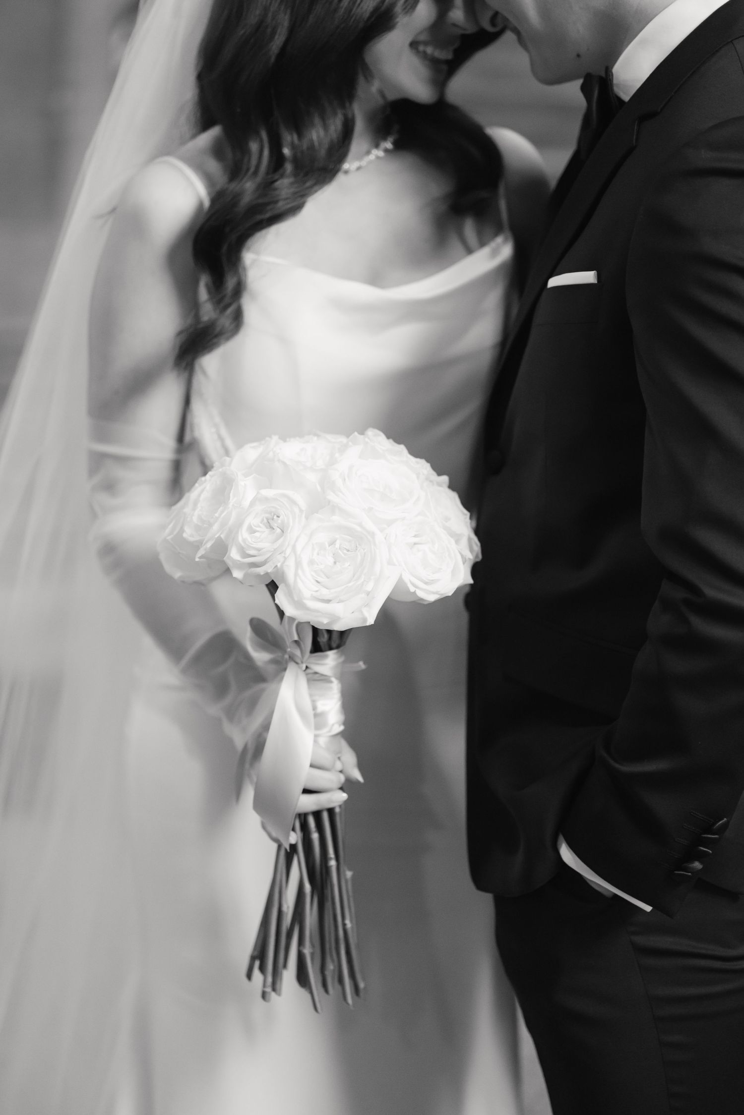 A black and white wedding detail shot featuring a classic white rose bouquet.