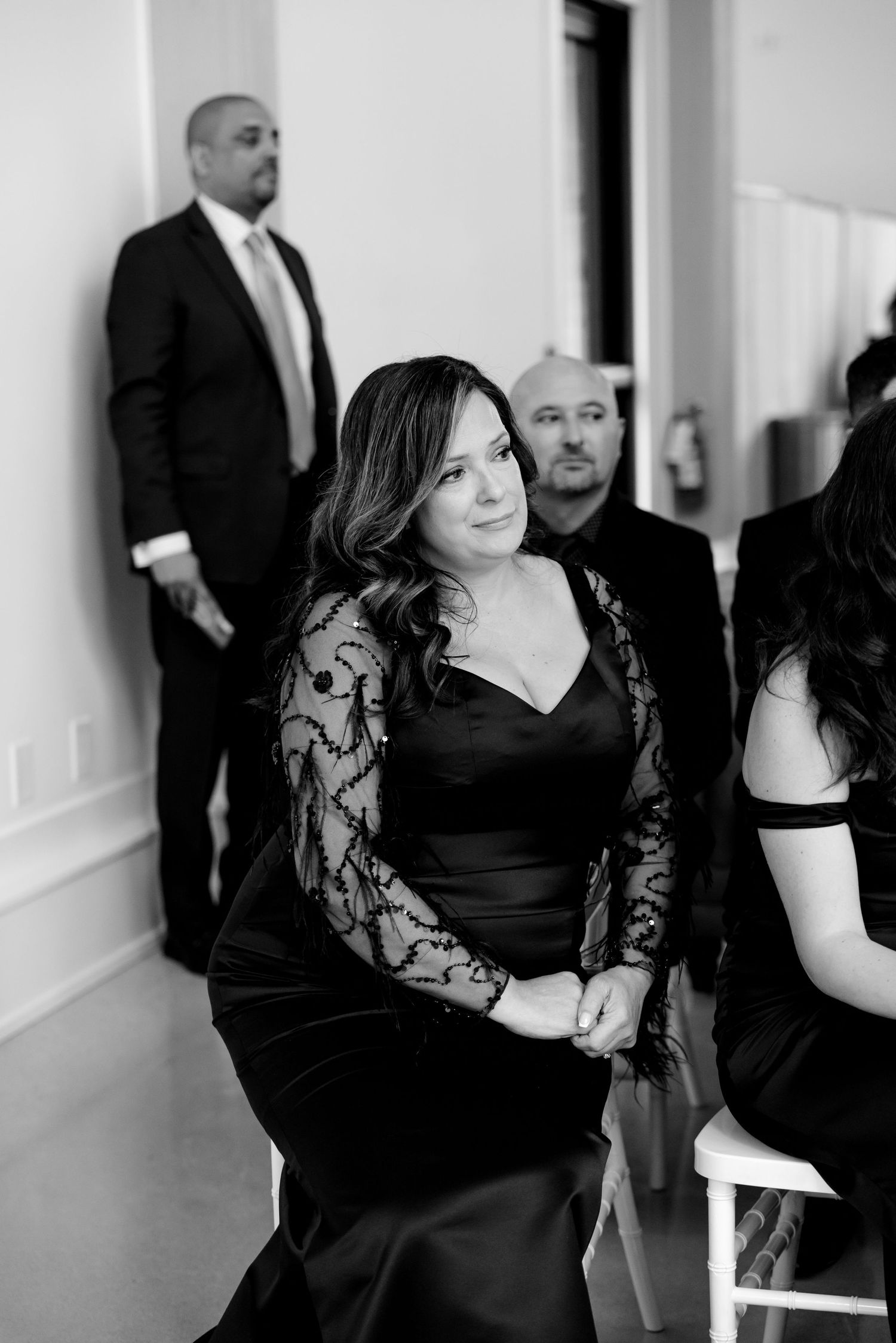 Wedding guest in a black lace dress seated during an elegant ceremony.