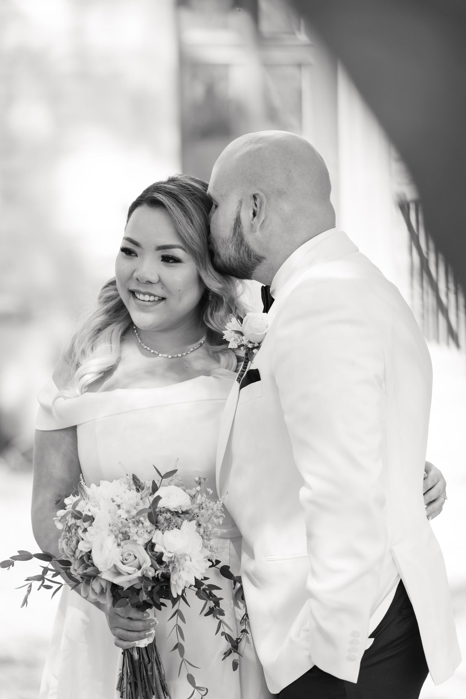 Black and white intimate wedding portrait showing tender moment between newlyweds.