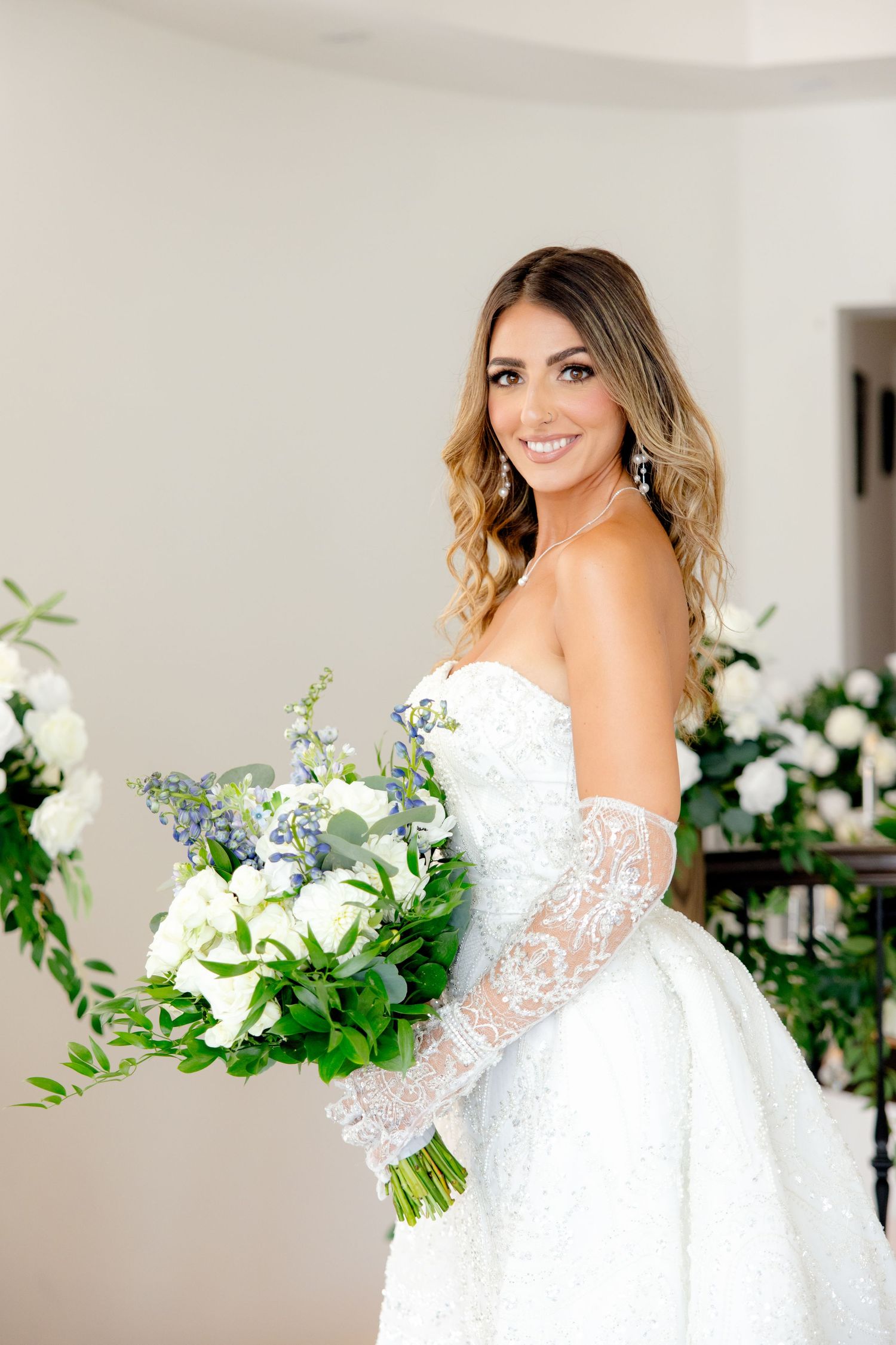 Bridal portrait with white and blue bouquet showing intricate lace wedding gown details.