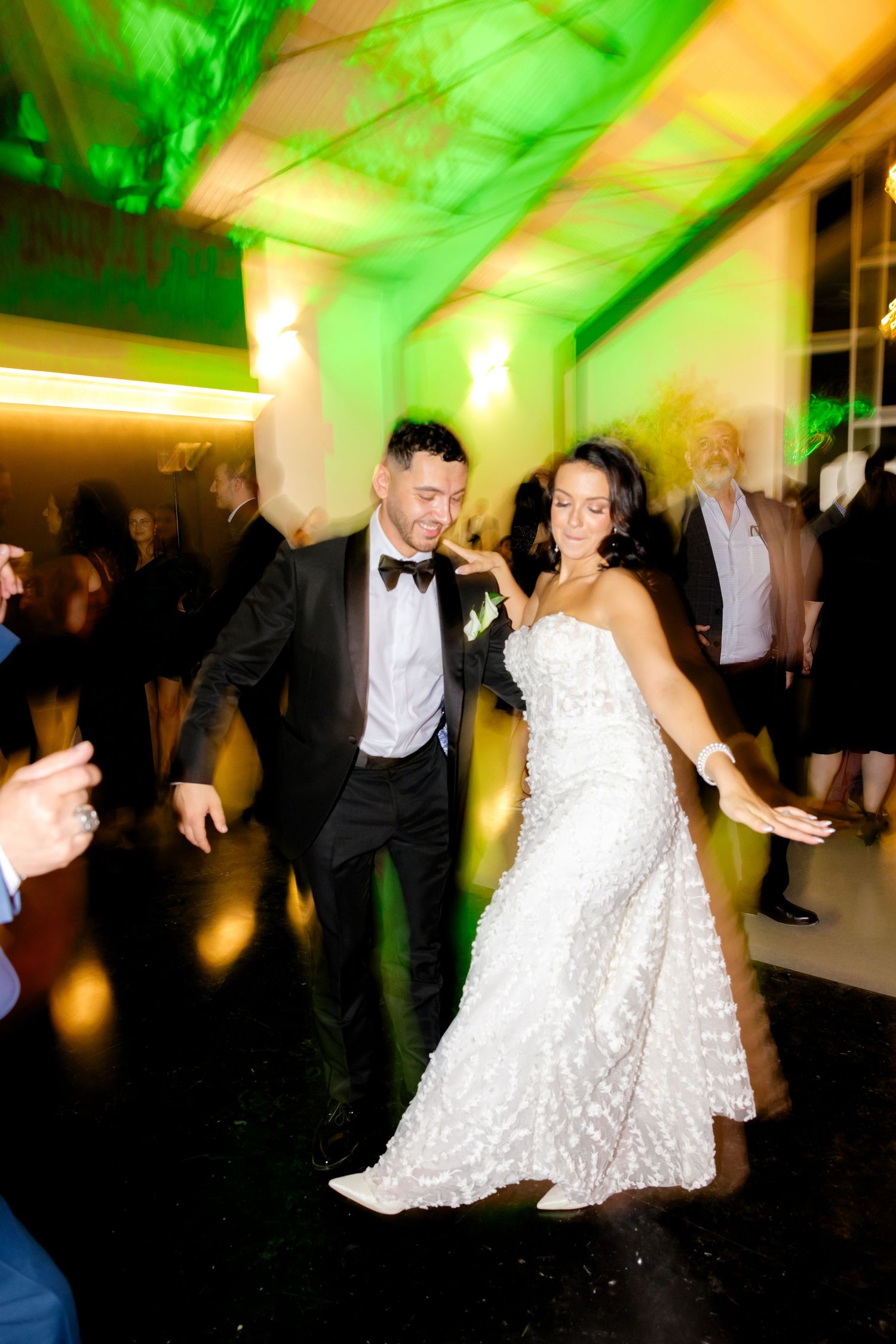 Dancing couple on reception floor under vibrant green and yellow lighting effects.