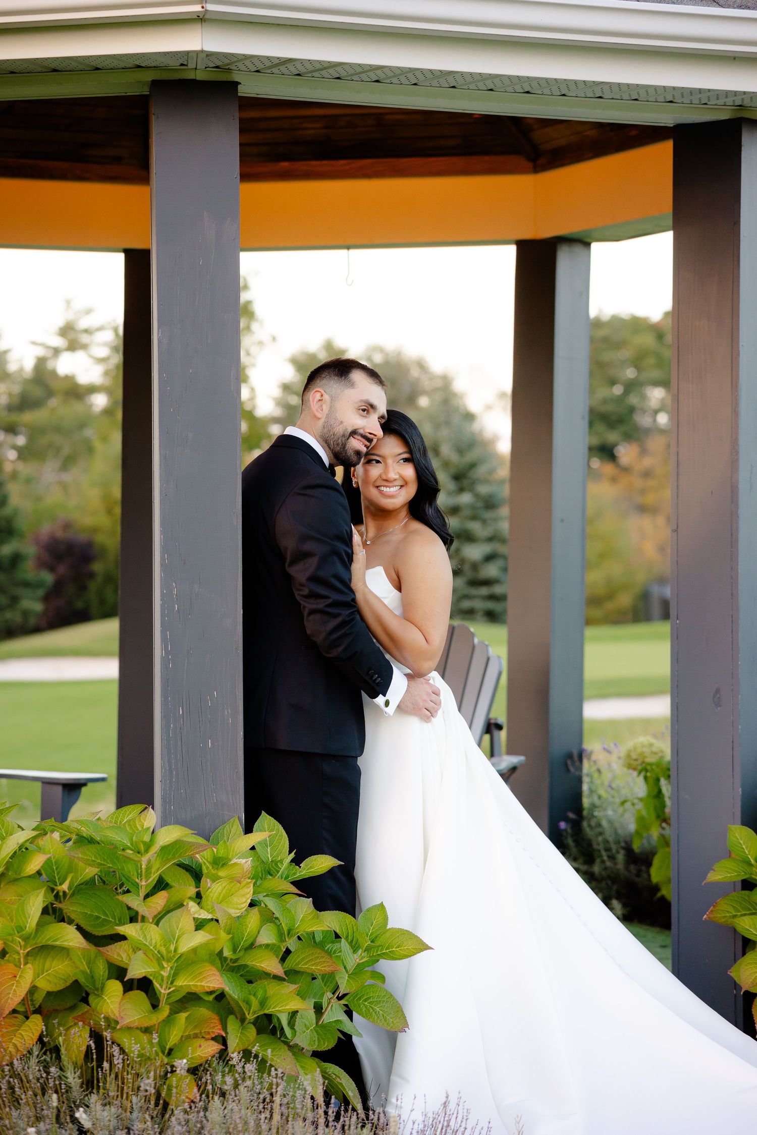 Couple shares intimate moment under covered porch with garden views at wedding venue.