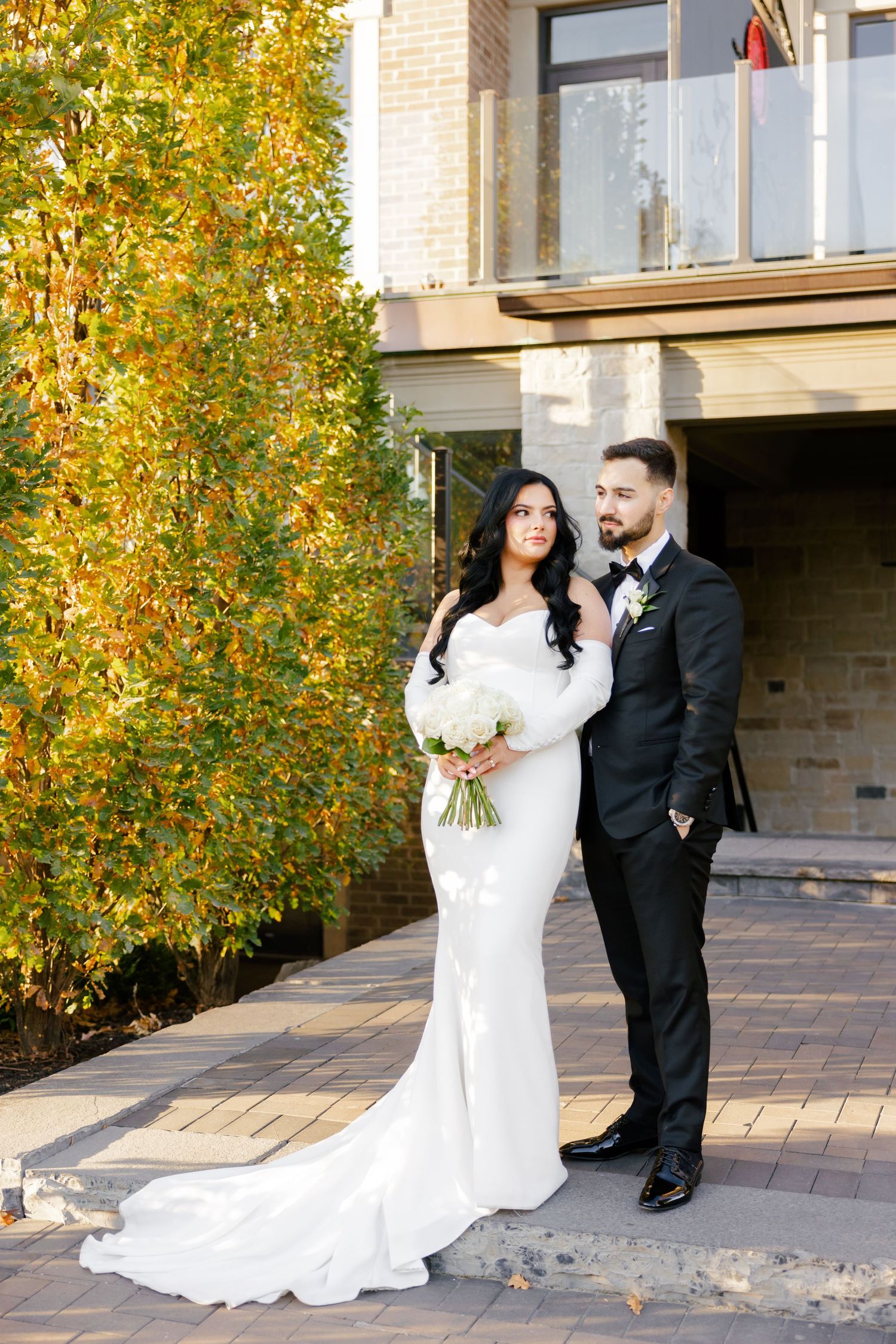 Elegant wedding portrait with golden fall foliage and modern architecture.
