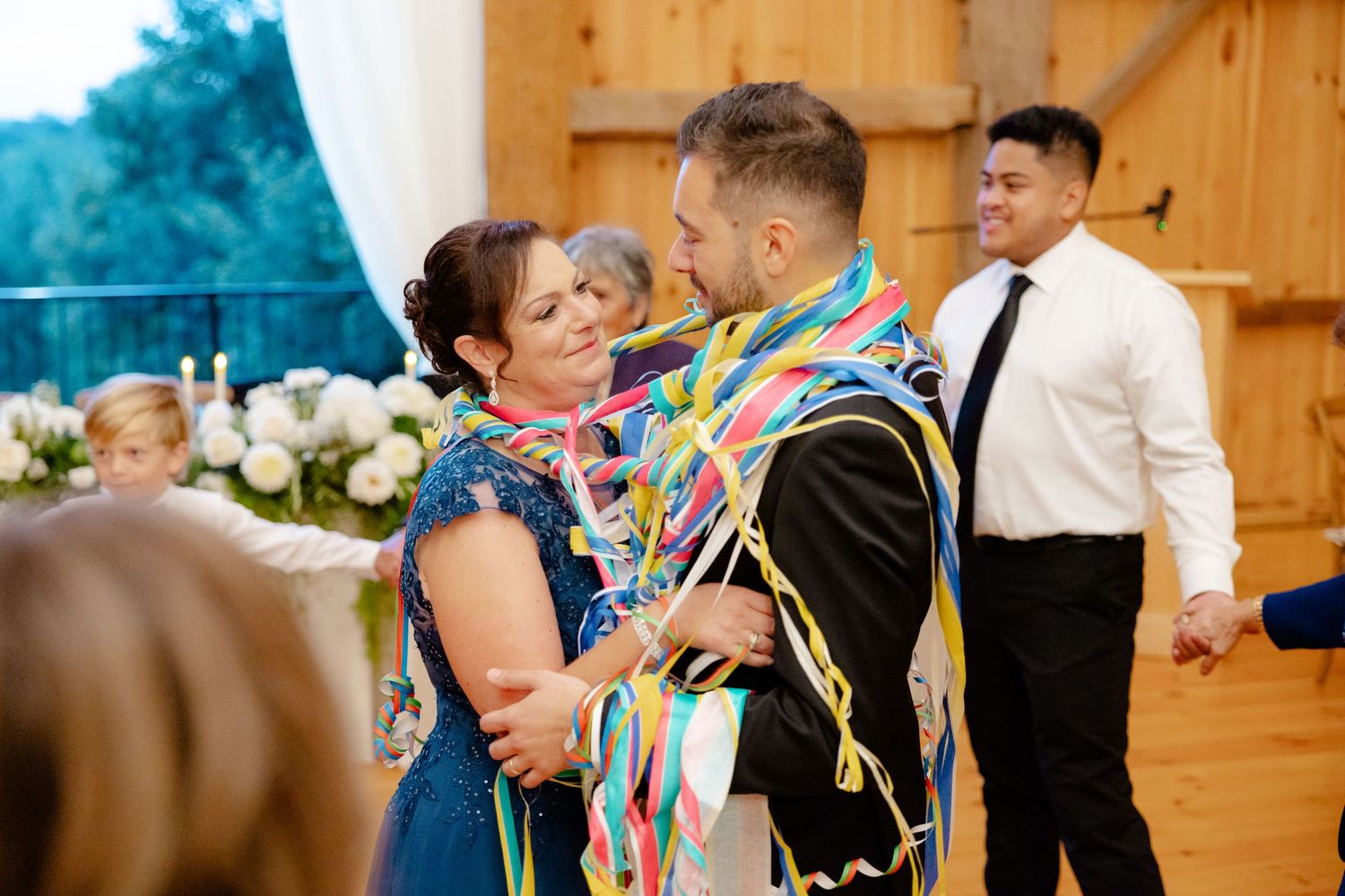 A celebratory dance with colorful ribbons at a rustic barn wedding reception.