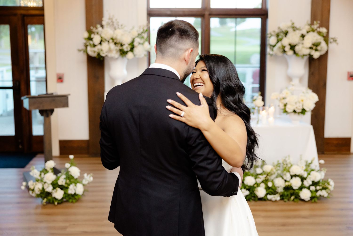 A romantic dance moment captured in a sunlit venue with white floral decorations.