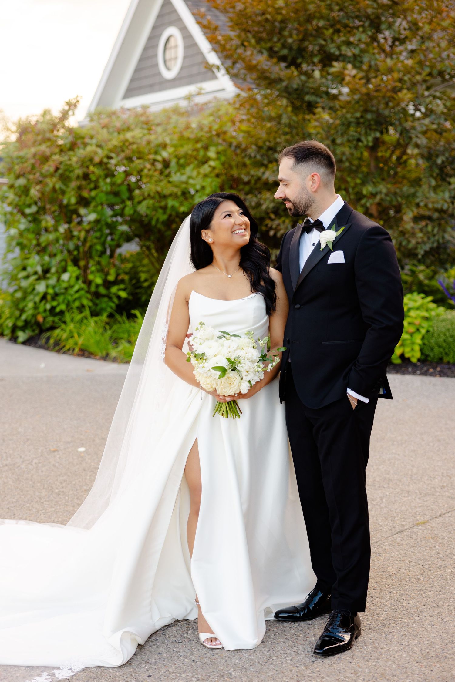 Elegant newlyweds share a romantic moment outside a stately venue with autumn trees.