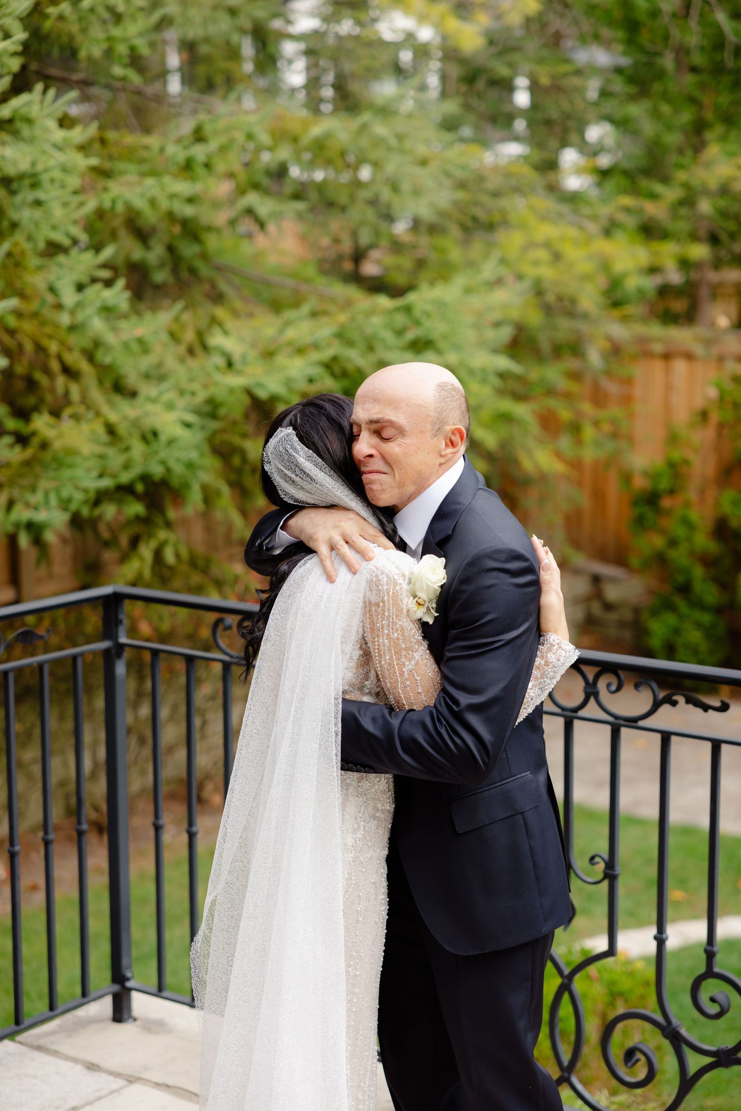 Emotional wedding moment shared between newlyweds on a stone patio with garden backdrop.