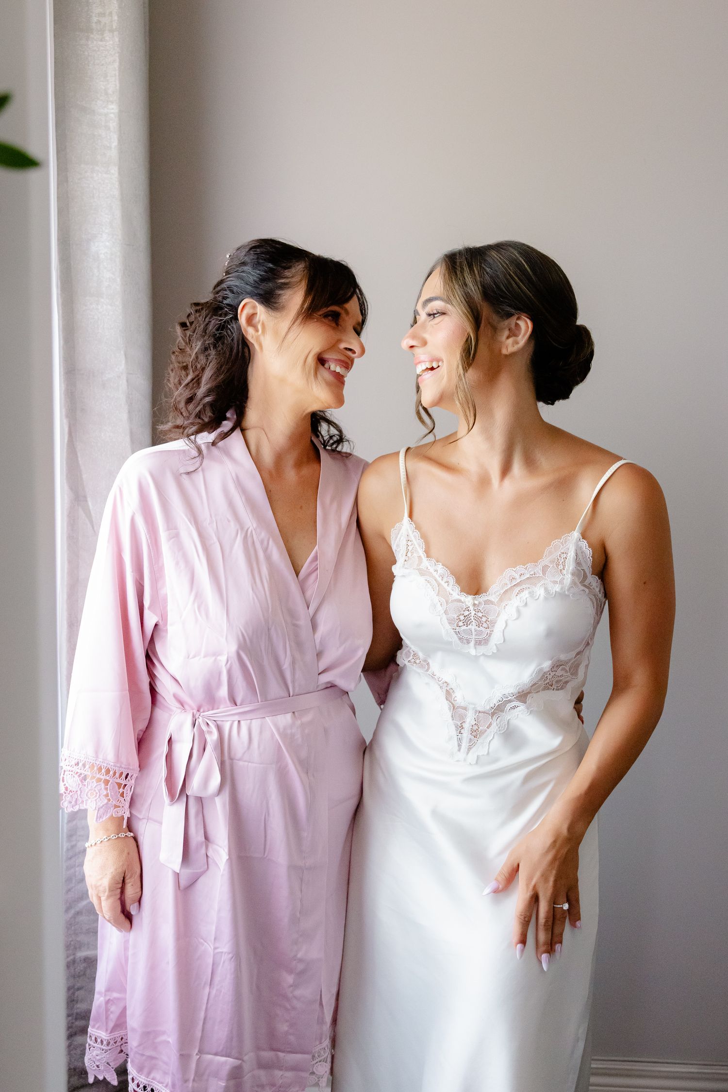Two people in pink and white robes share joyful laughter during a candid photo sequence.