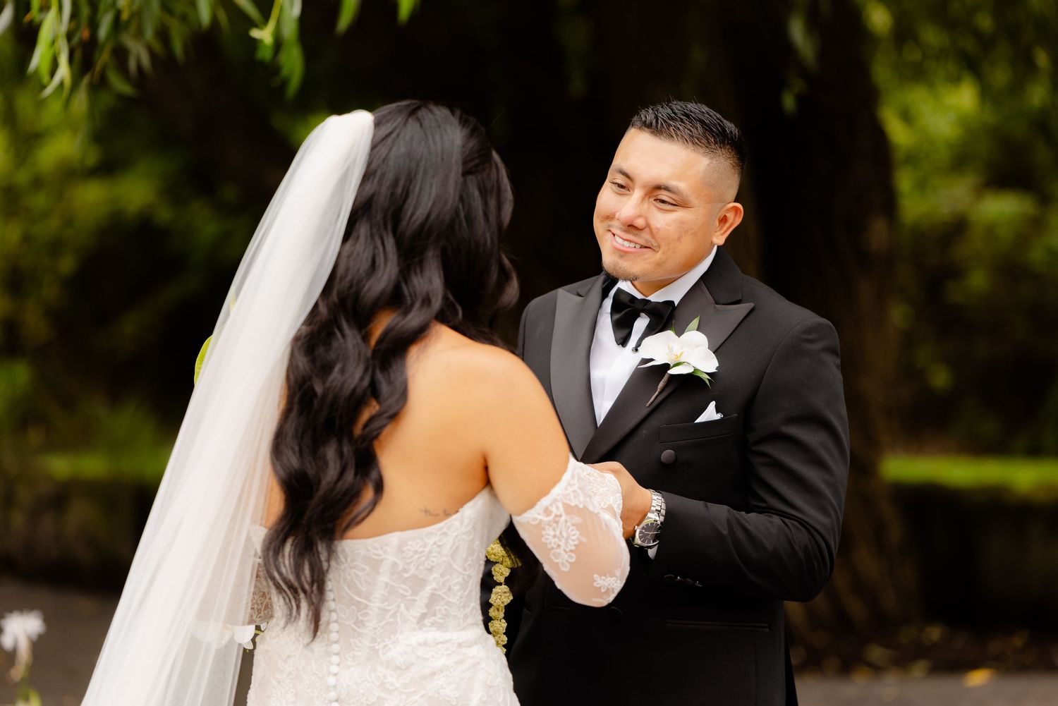 Newlyweds share their first dance together at an outdoor wedding reception surrounded by lush greenery.